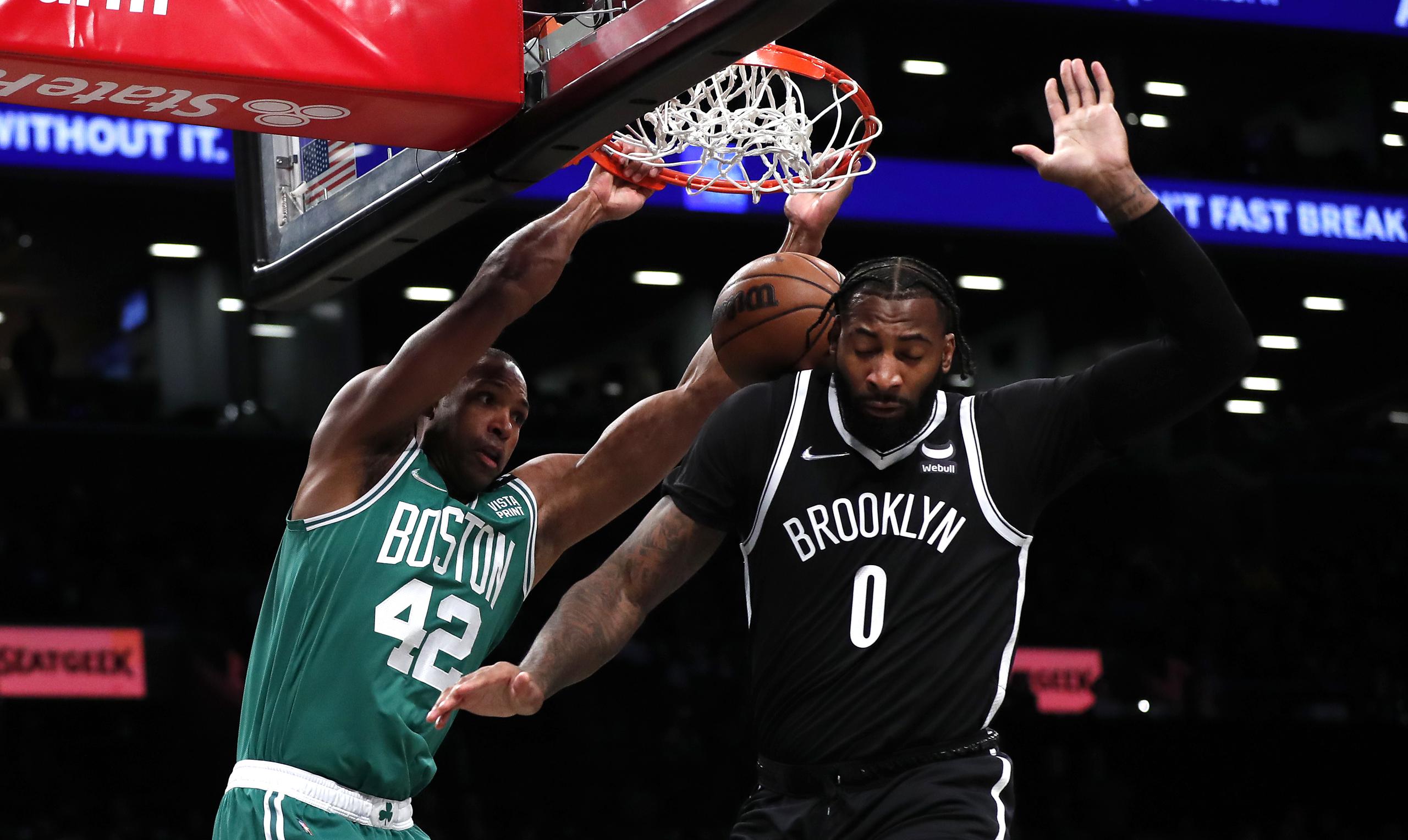 El centro de los Celtics de Boston, Al Horford (42), realiza un espectacular donqueo mientras el defensor de los Nets de Brooklyn, Andre Drummond, se sale del camino sin poder hacer mucho.