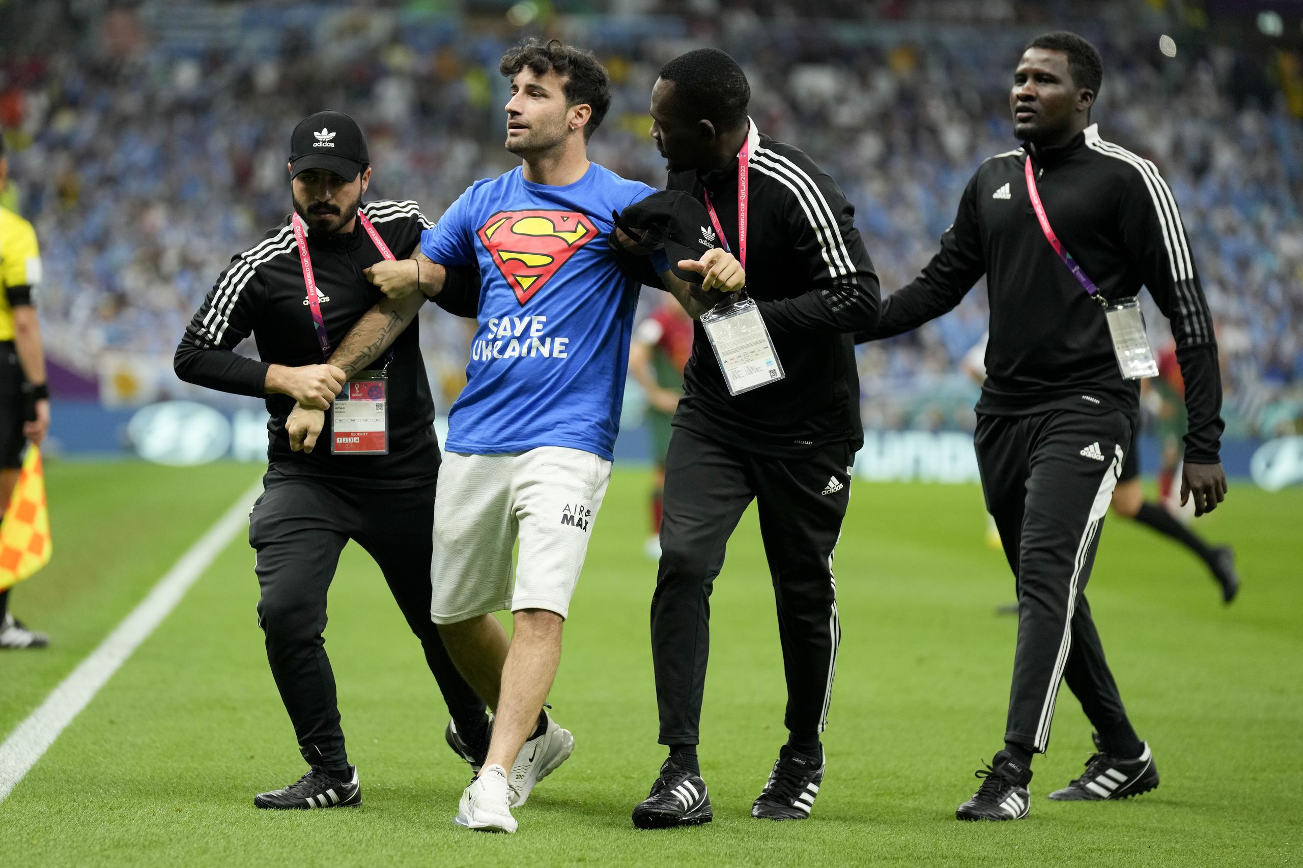 Un aficionado es detenido tras irrumpir en la cancha con la bandera arcoíris durante el partido del Grupo H entre Portugal y Uruguay, el lunes 28 de noviembre de 2022, en Lusail, Qatar. (AP Foto/Aijaz Rahi)