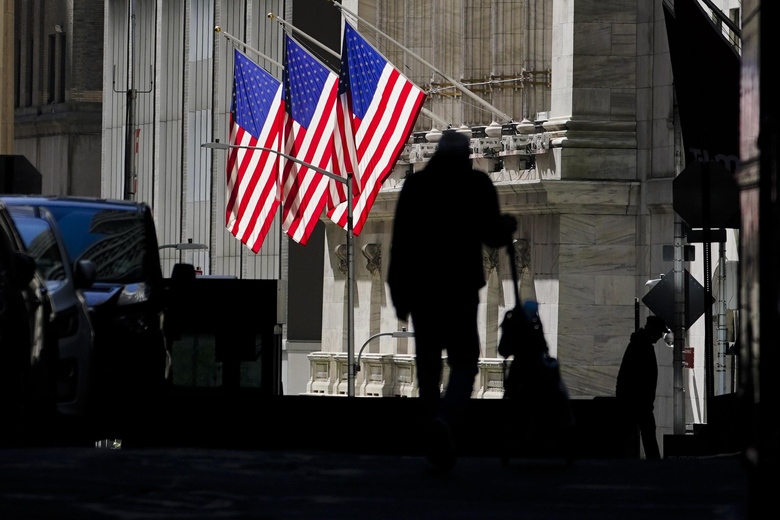 Dos personas caminando frente a la Bolsa de Valores de Nueva York.