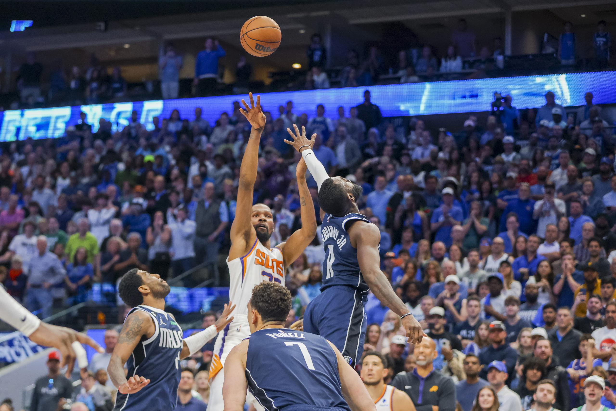 Kevin Durant, de los Suns de Phoenix, atrás en el centro, tira la canasta ganadora del partido sobre los Mavericks de Dallas, ante el intento de bloqueo de Tim Hardaway Jr., derecha, y Kyrie Irving, izquierda, durante la segunda mitad del juego de baloncesto de la NBA.
