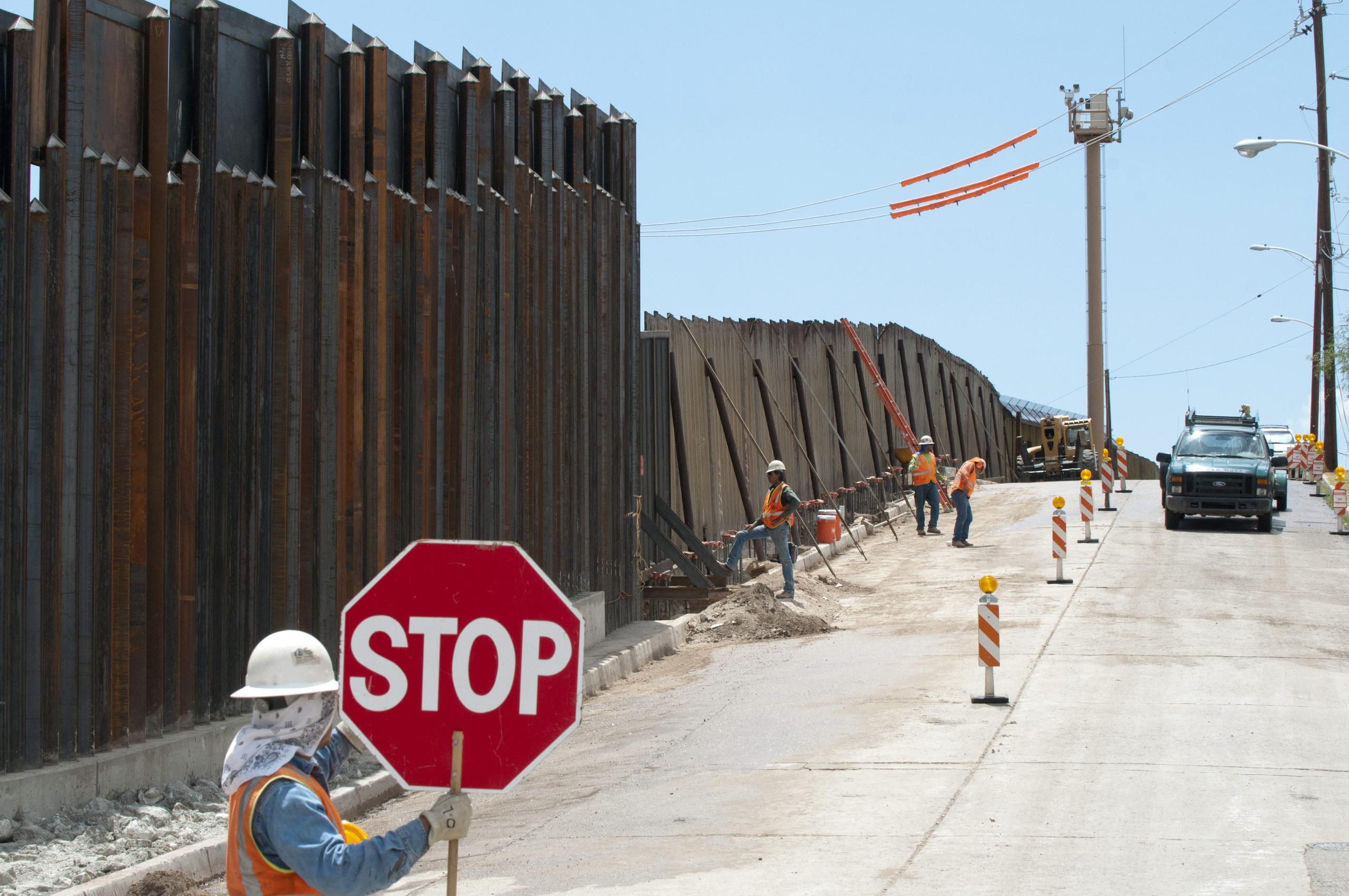 Fotografía de archivo de unos trabajadores finalizan un trozo del muro fronterizo que separa México de Estados Unidos.