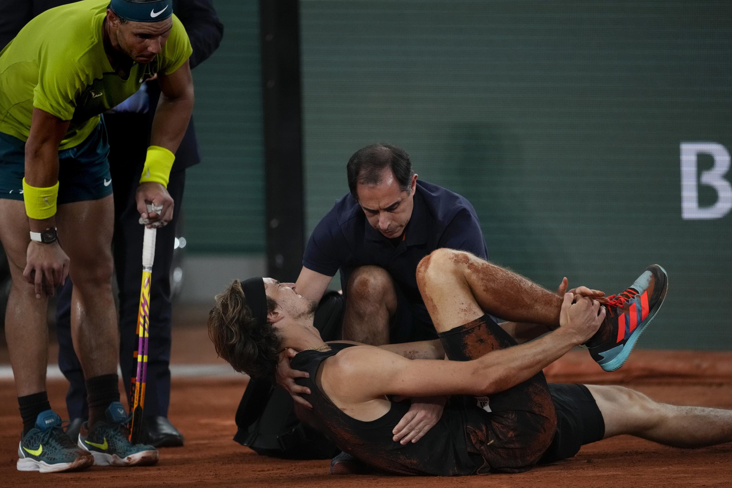 Rafael Nadal observa mientras Alexander Zverev es atendido.