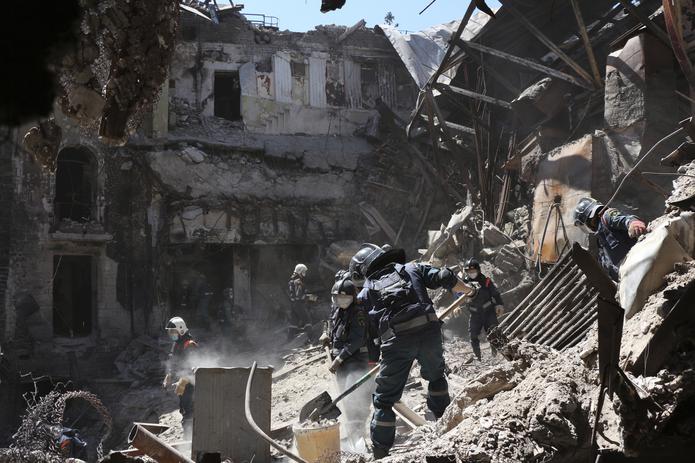 Operarios del Ministerio de Situaciones de Emergencia de la República Popular de Donetsk retiran escombros en un teatro de Mariúpol dañado por los intensos combates por la ciudad, en territorio controlado por la República Popular de Donetsk, en el este de Ucrania, el 12 de mayo de 2022. (AP Foto)