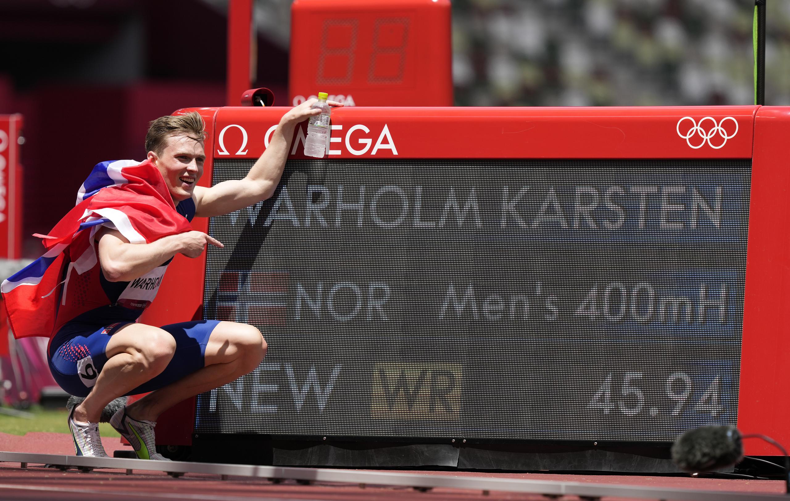 Karsten Warholm posa junto a la pizarra que despliega su nueva marca mundial en los 400 metros con vallas.