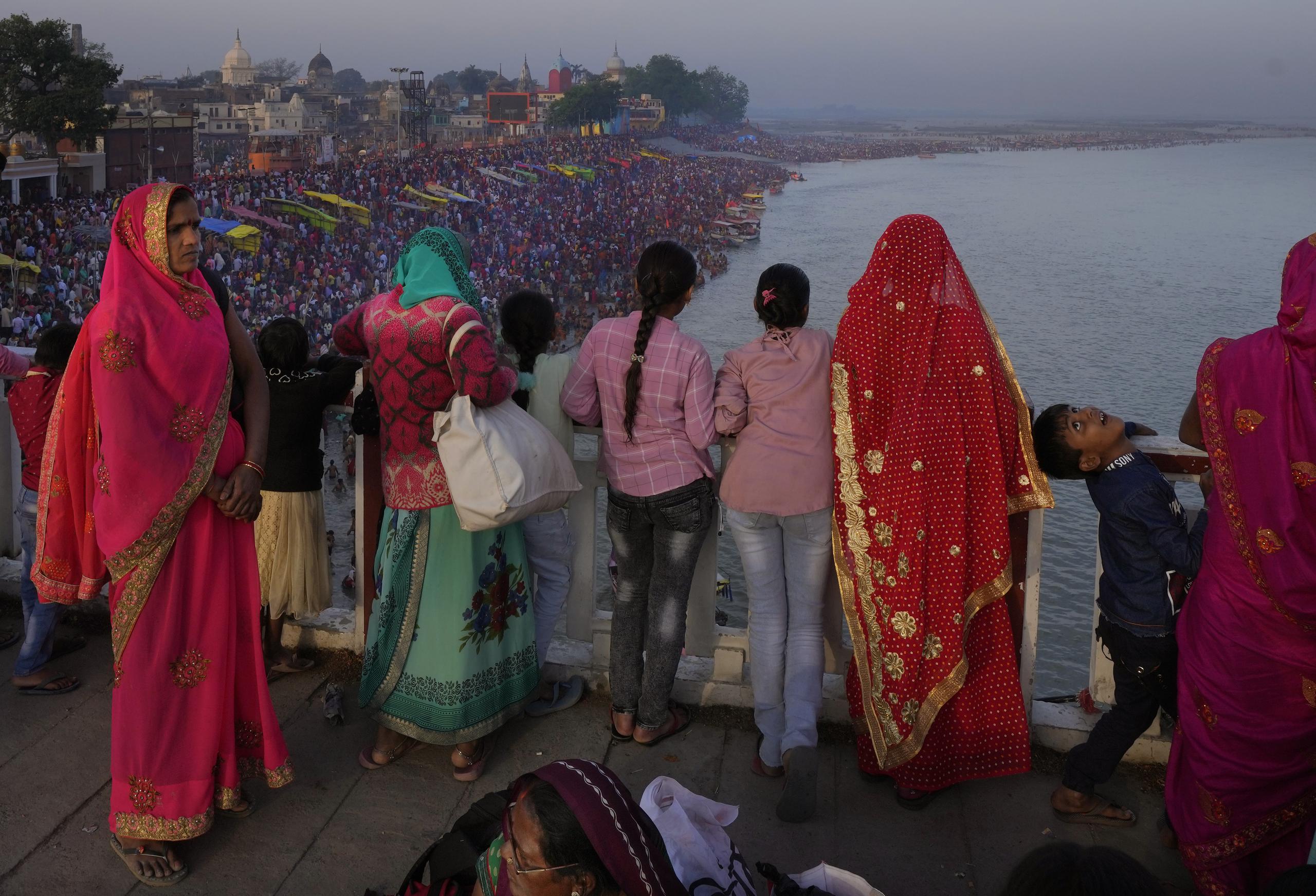 Familias observan desde un puente mientras miles de personas entran al río sagrado Saryu en Ayodhya, India, el 30 de marzo de 2023. (Foto AP /Manish Swarup)
