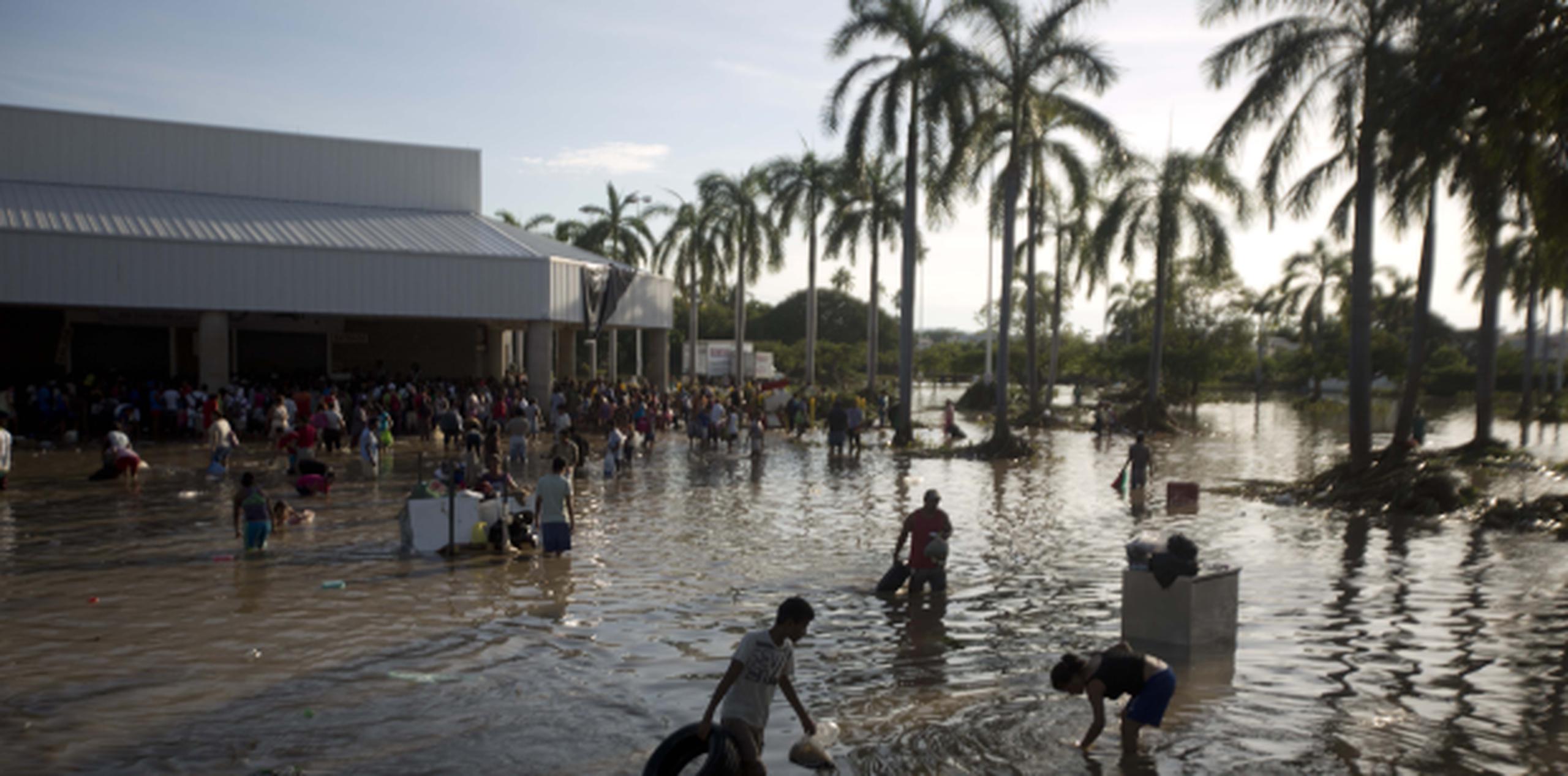 Cientos de personas caminaban entre las aguas estancadas del estacionamiento del almacén en busca de cualquier cosa. (AP/Eduardo Verdugo)