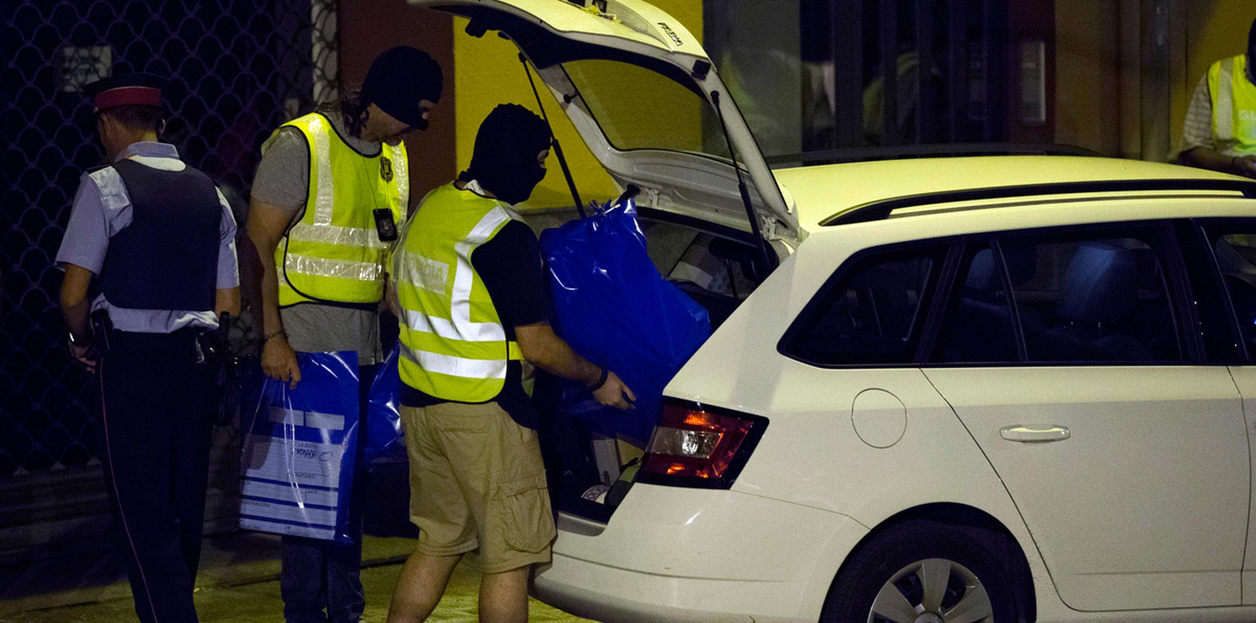 Policías colcan bolsas dentro de un auto durante un registro en un cibercafé en Ripoll, España. (AP)