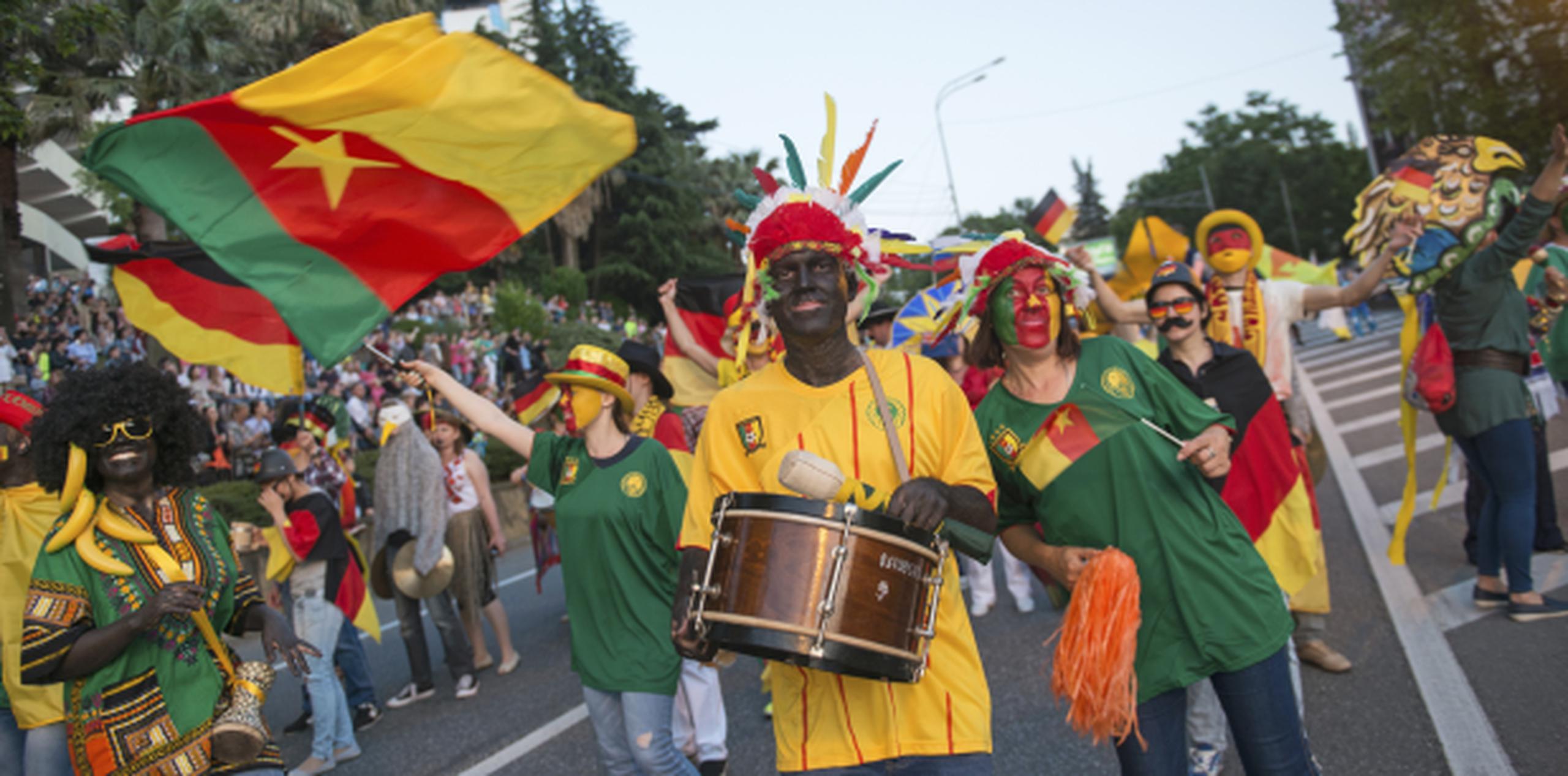 Personas con la cara pintada de negro y ropas africanas, llevando la bandera de Camerún, participaron en un desfile en Sochi, previo a los partidos de la Copa Confederaciones. (AP/Artur Lebedev)
