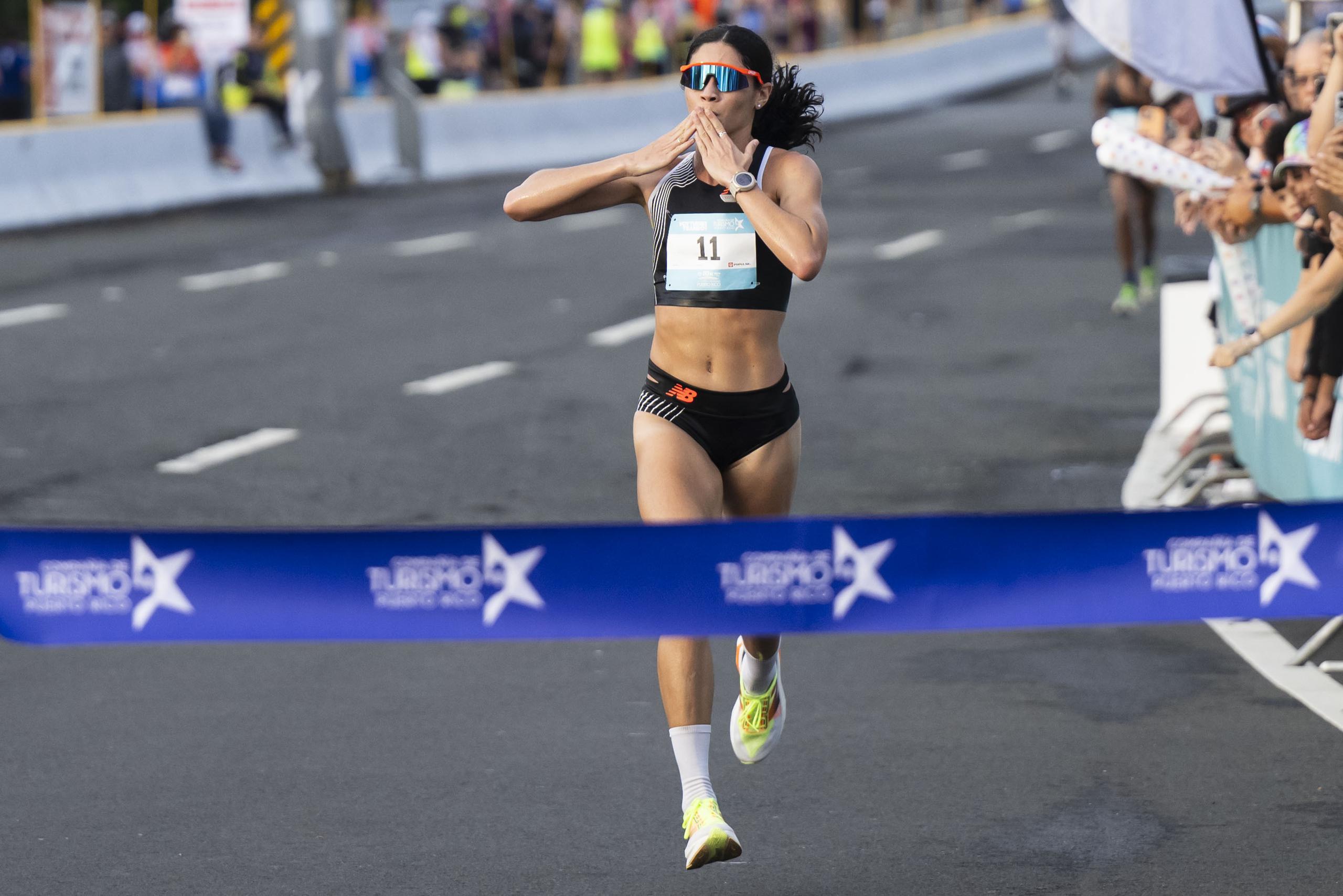 La veterana fondista Beverly Ramos envía saludos a su público al llegar primera en su rama del Puerto Rico 10k Run.