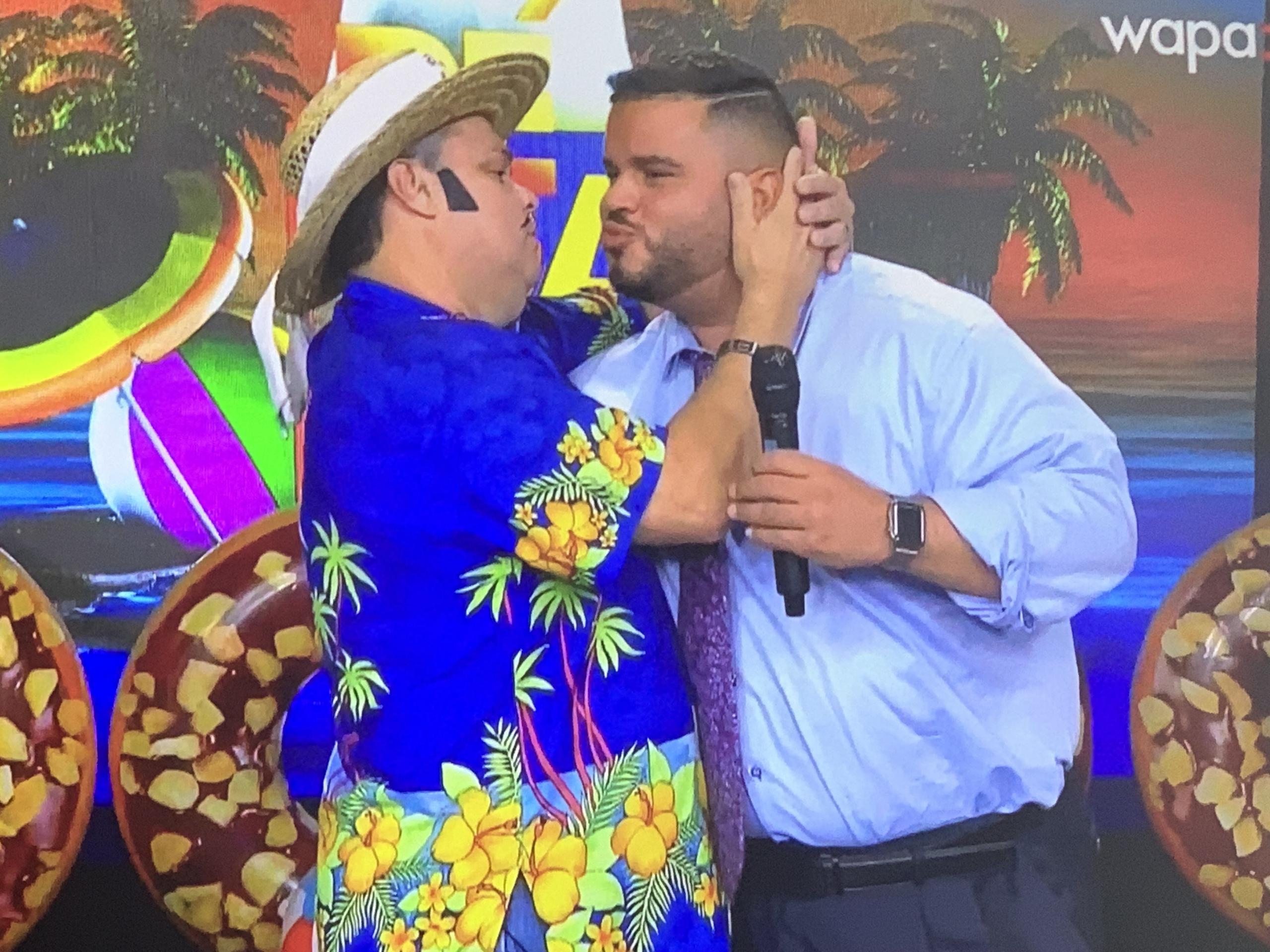 El analista político Jay Fonseca y el personaje de El Guitarreño intentan darse un beso en la mejilla tras zanjar sus diferencias ante las cámaras de Wapa TV.