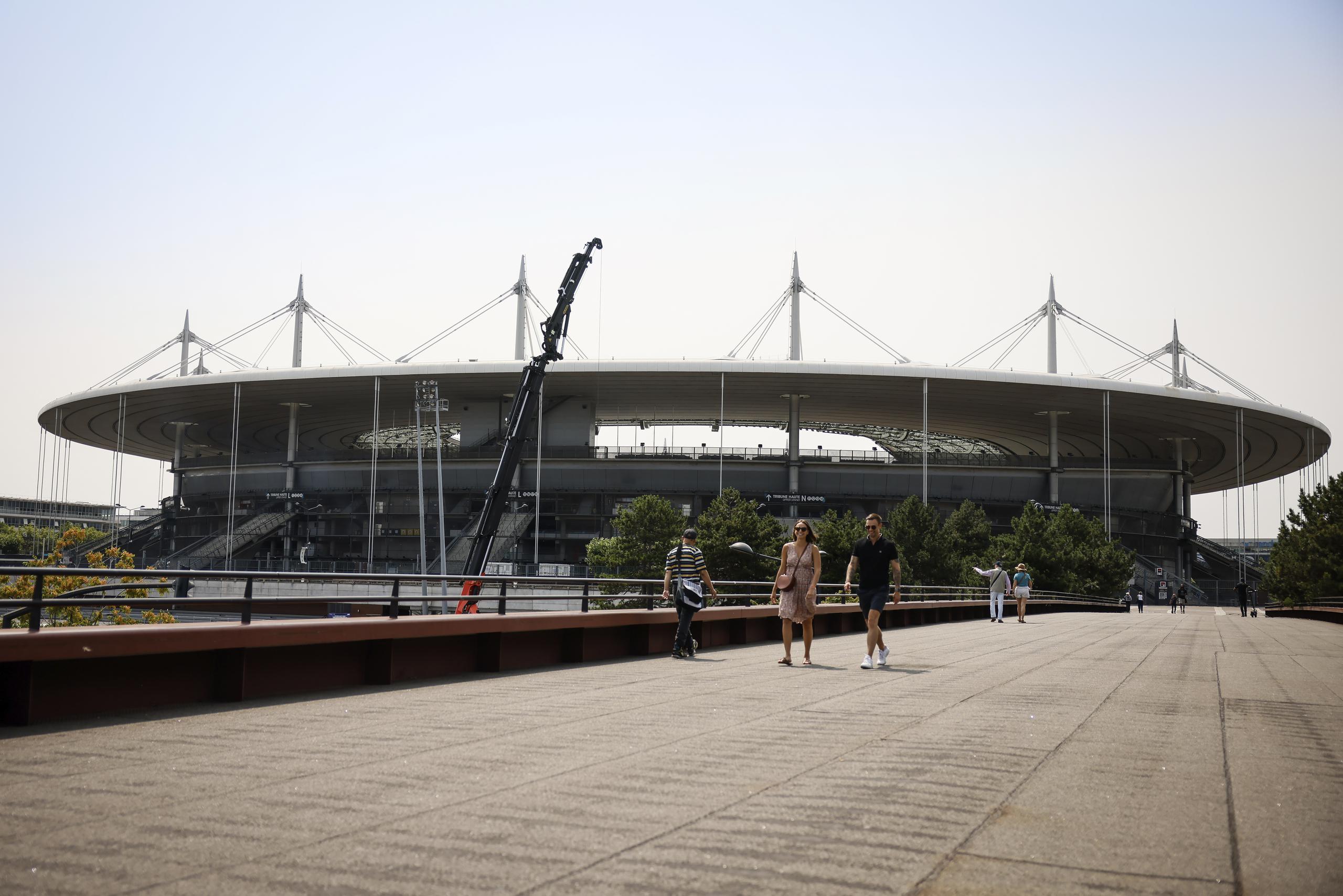 Gente camina cerca del Stade de France, el lunes 10 de julio de 2023 en Saint-Denis. El estadio será la sede del atletismo y el rugby de siete en los Juegos Olímpicos de París 2024. (AP Foto/Thomas Padilla)