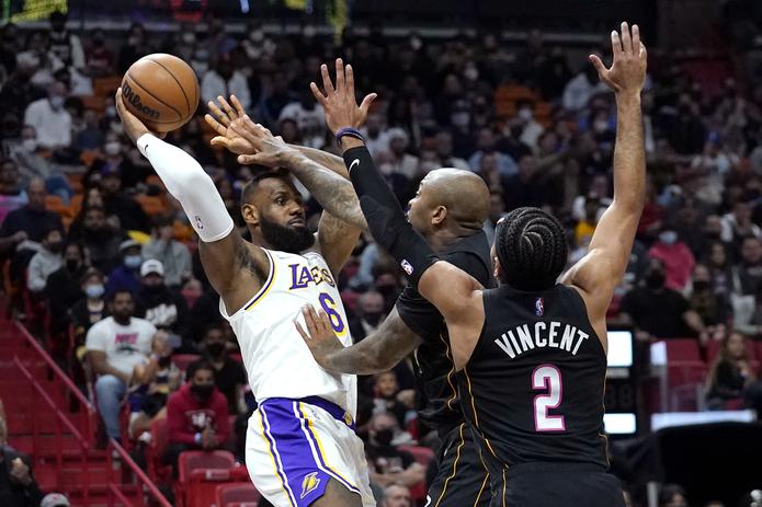 LeBron James (6), de los Lakers de Los Ángeles, intenta pasar el balón con la marca de P.J. Tucker, centro, y Gabe Vincent (2), del Heat de Miami, durante la primera mitad del juego de la NBA en Miami.