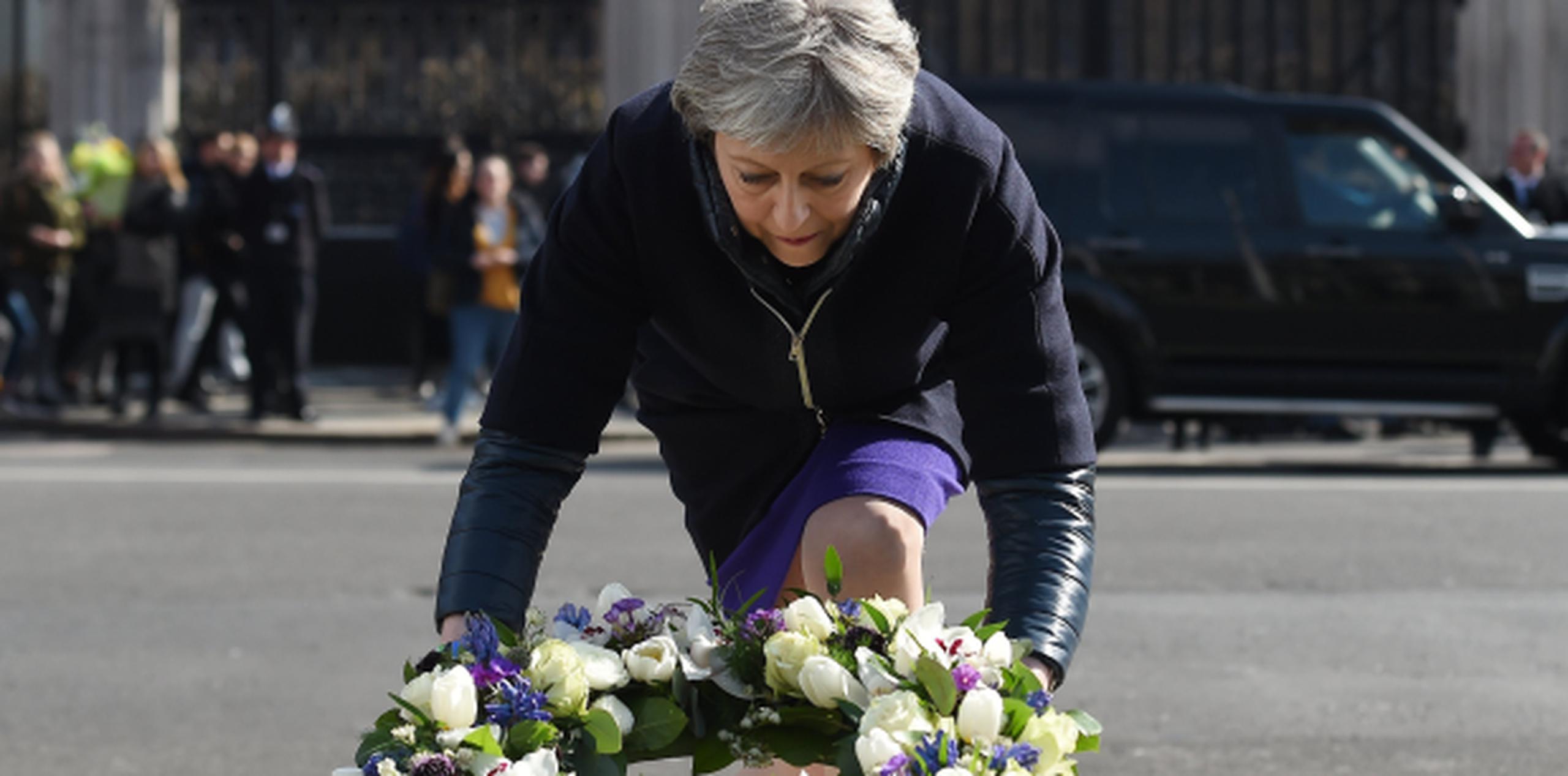La primera ministra británica, Theresa May, coloca flores en honor a las víctimas del ataque terrorista del puente de Westminister, en el exterior del Parlamento en Londres (Reino Unido). (EFE)