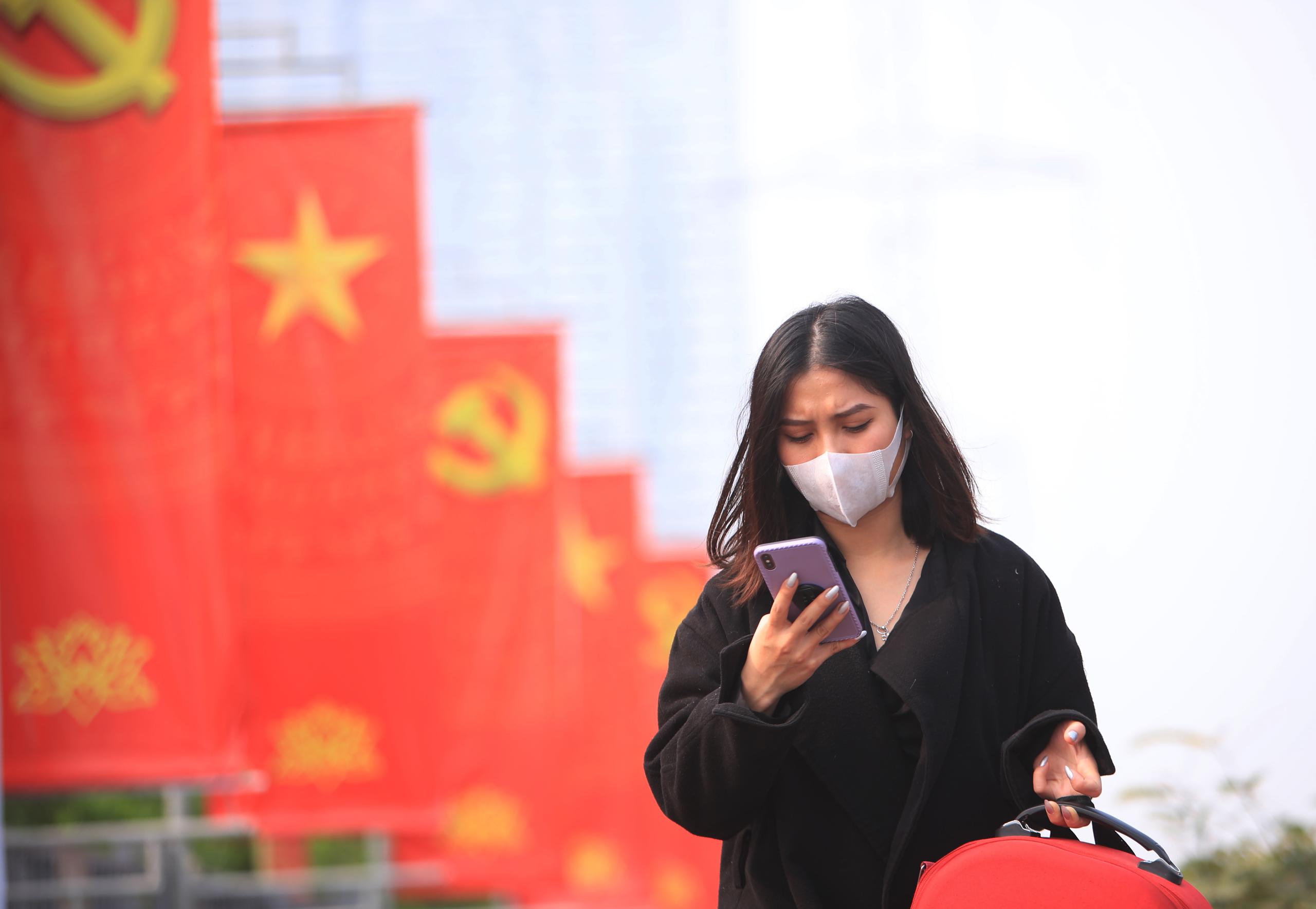 Una mujer con mascarilla viendo su teléfono en Hanoi, Vietnam.