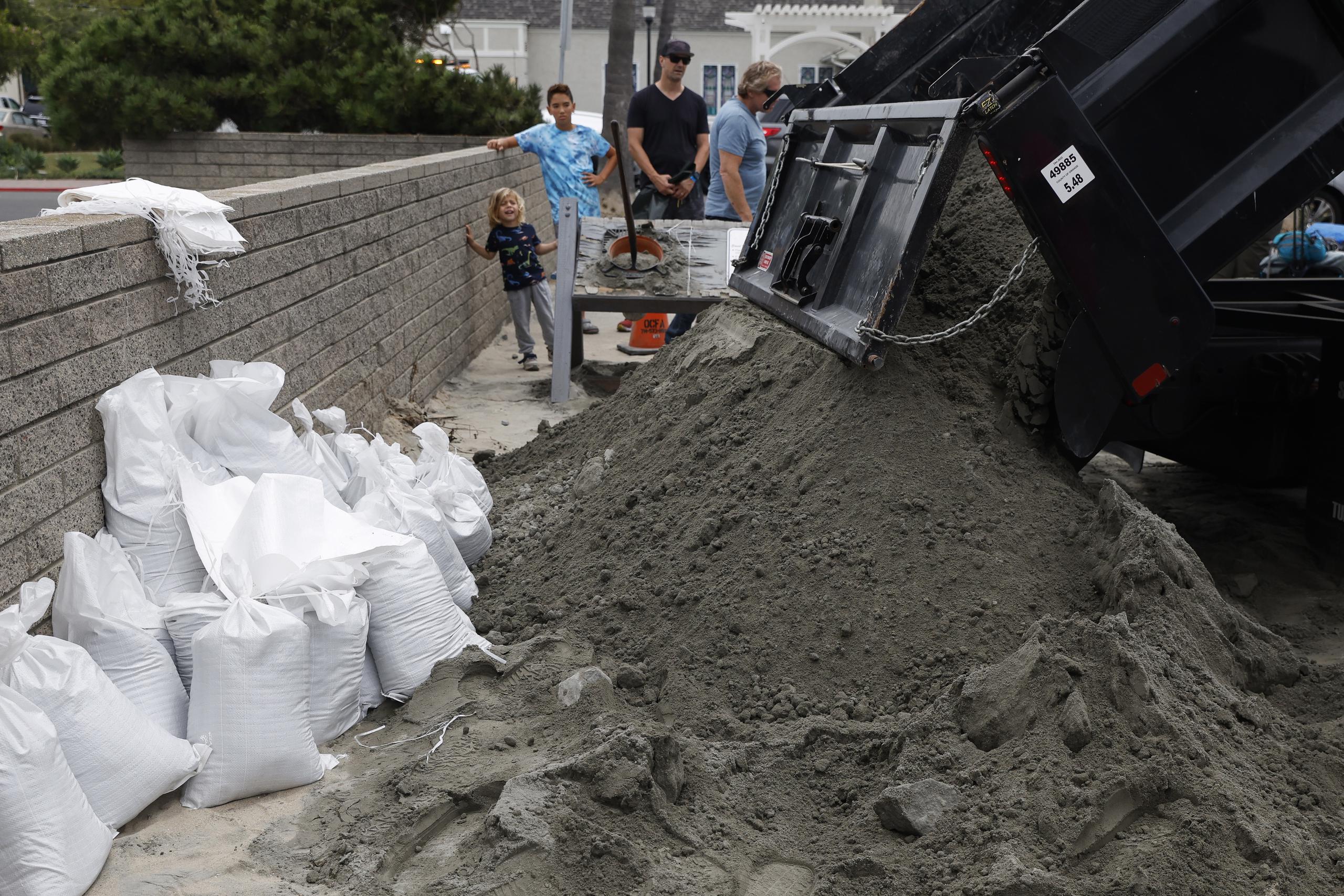 Un camión arroja arena en una estación de bomberos local donde los residentes pueden llenar bolsas de arena para ayudar a fortalecer sus hogares, en Seal Beach, California.