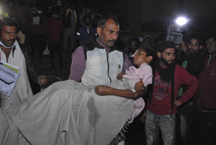 Un hombre lleva en brazos a una niña del Hospital Infantil Kamla Nehru tras un incendio en la unidad de neonatología en Bhopal, India, el lunes 8 de noviembre de 2021. (AP Foto)