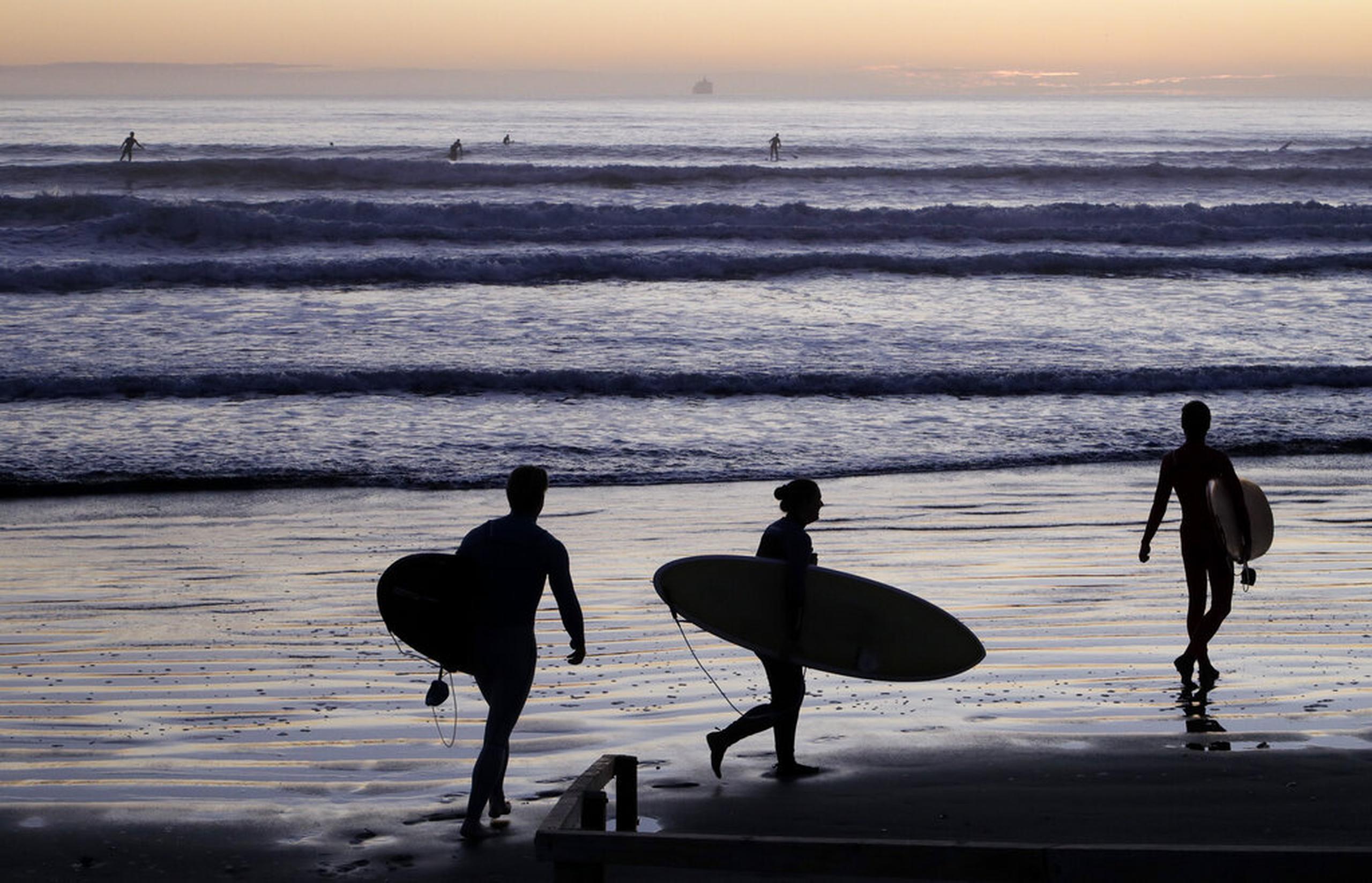 Surfistas disfrutaron hoy de la playa Sumner tras el alivio de las restricciones, en Christchurch, Nueva Zelanda.