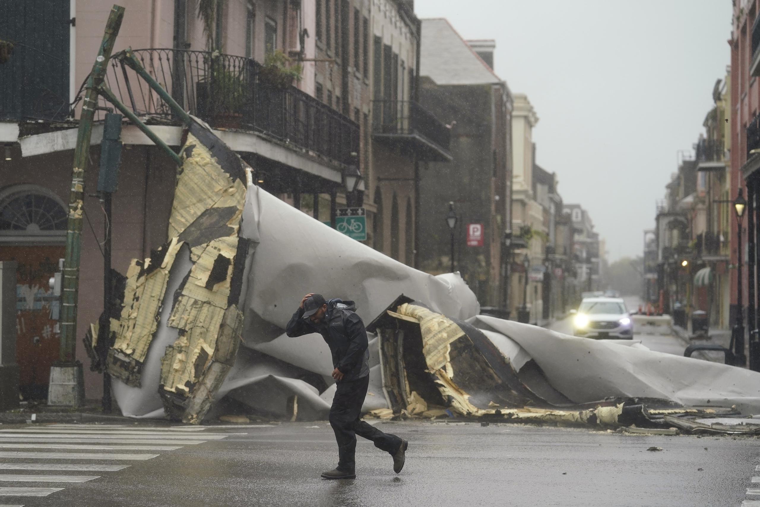 Un hombre pasa por una sección del techo que se desprendió de un edificio en el Barrio Francés por los vientos del huracán Ida, en Nueva Orleans.