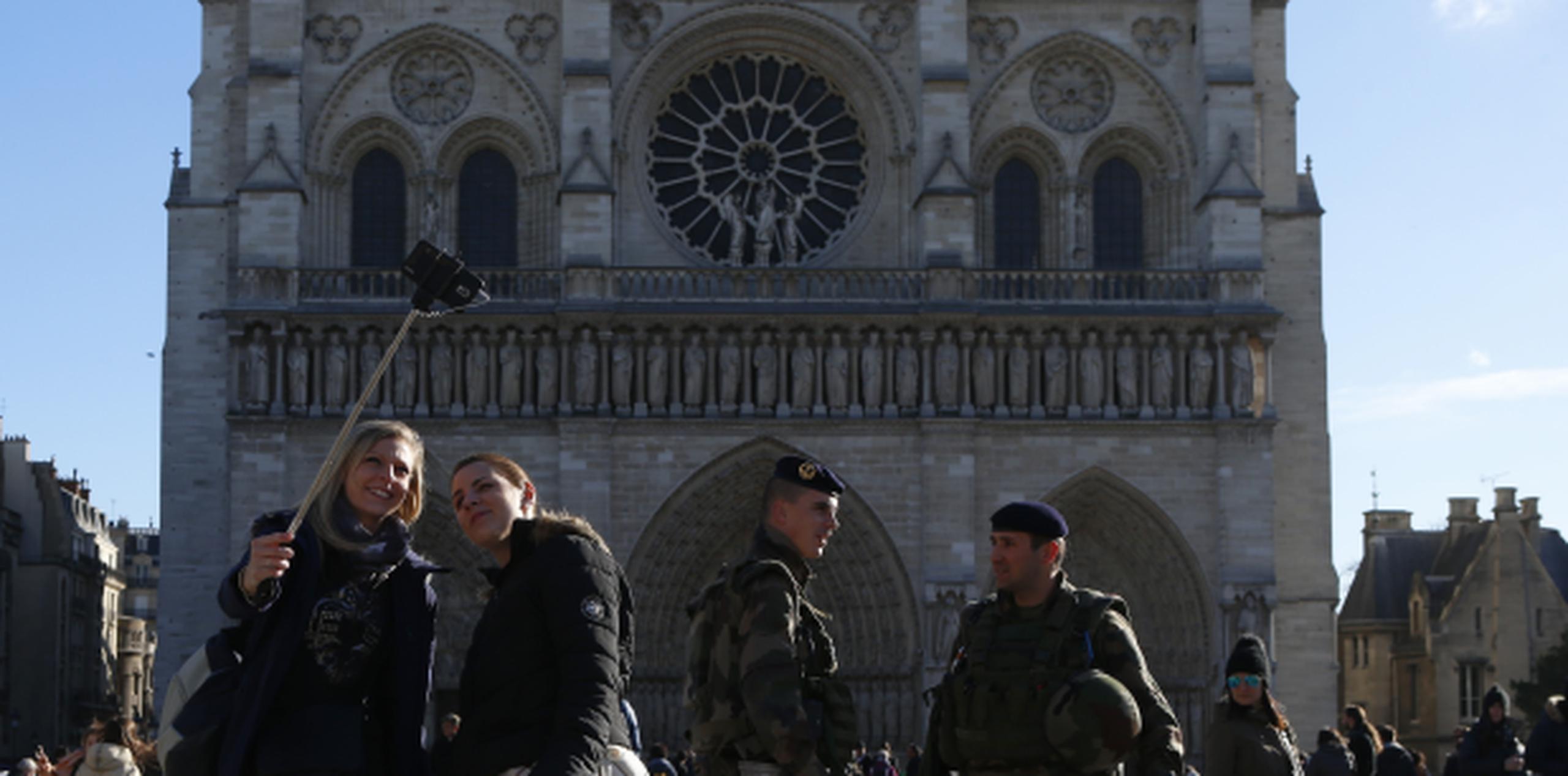 Soldados franceses prestan vigiancia frente a la catedral de Notre Dame en París, mientras una pareja posan para un 'selfie'. (AP)