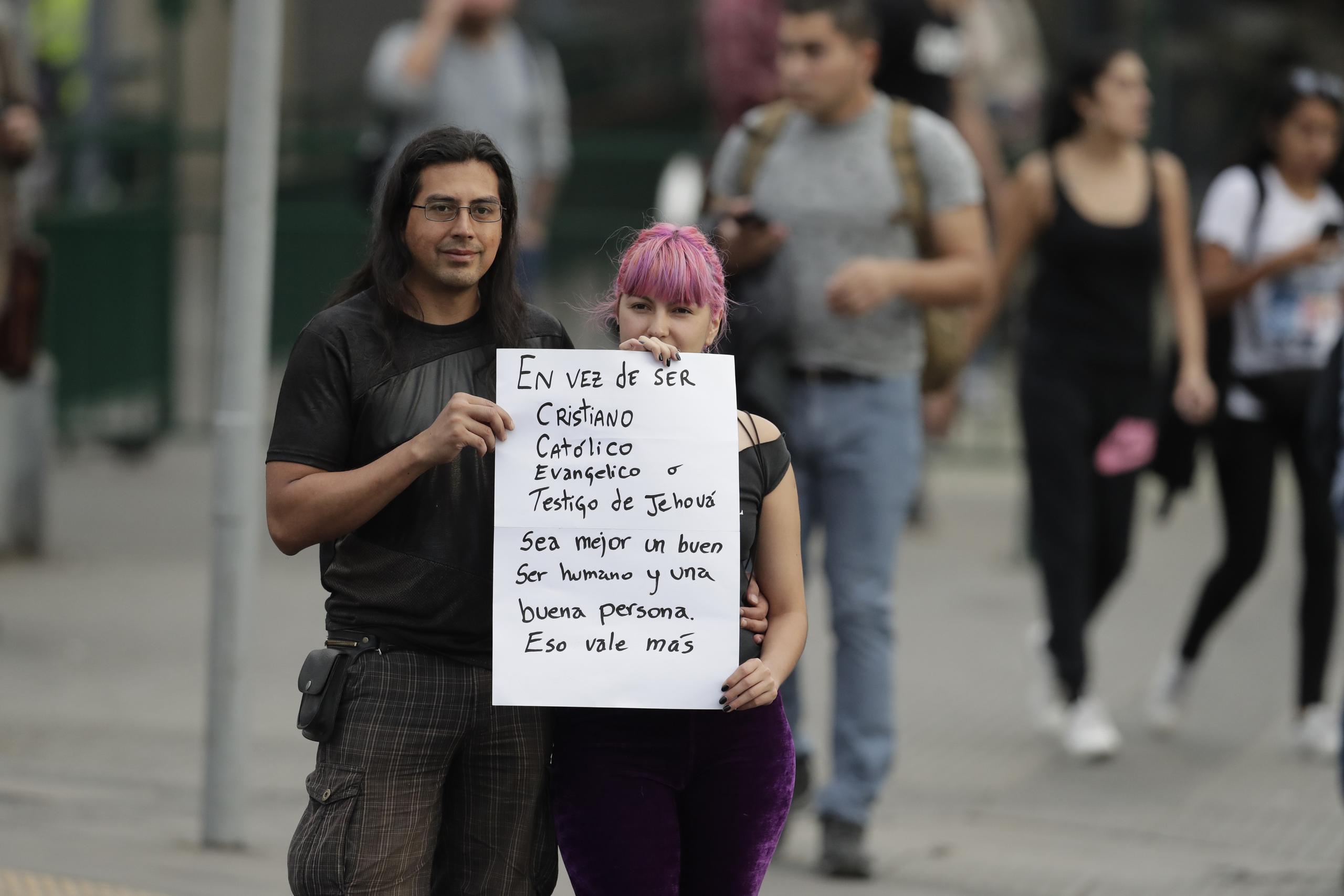 Una pareja que espera al papa Francisco en Santiago de Chile sostiene una pancarta en la que se lee: "En vez de ser cristiano, católico, evangélico o testigo de Jehová, sea mejor un buen ser humano y una buena persona. Eso vale más". (AP)