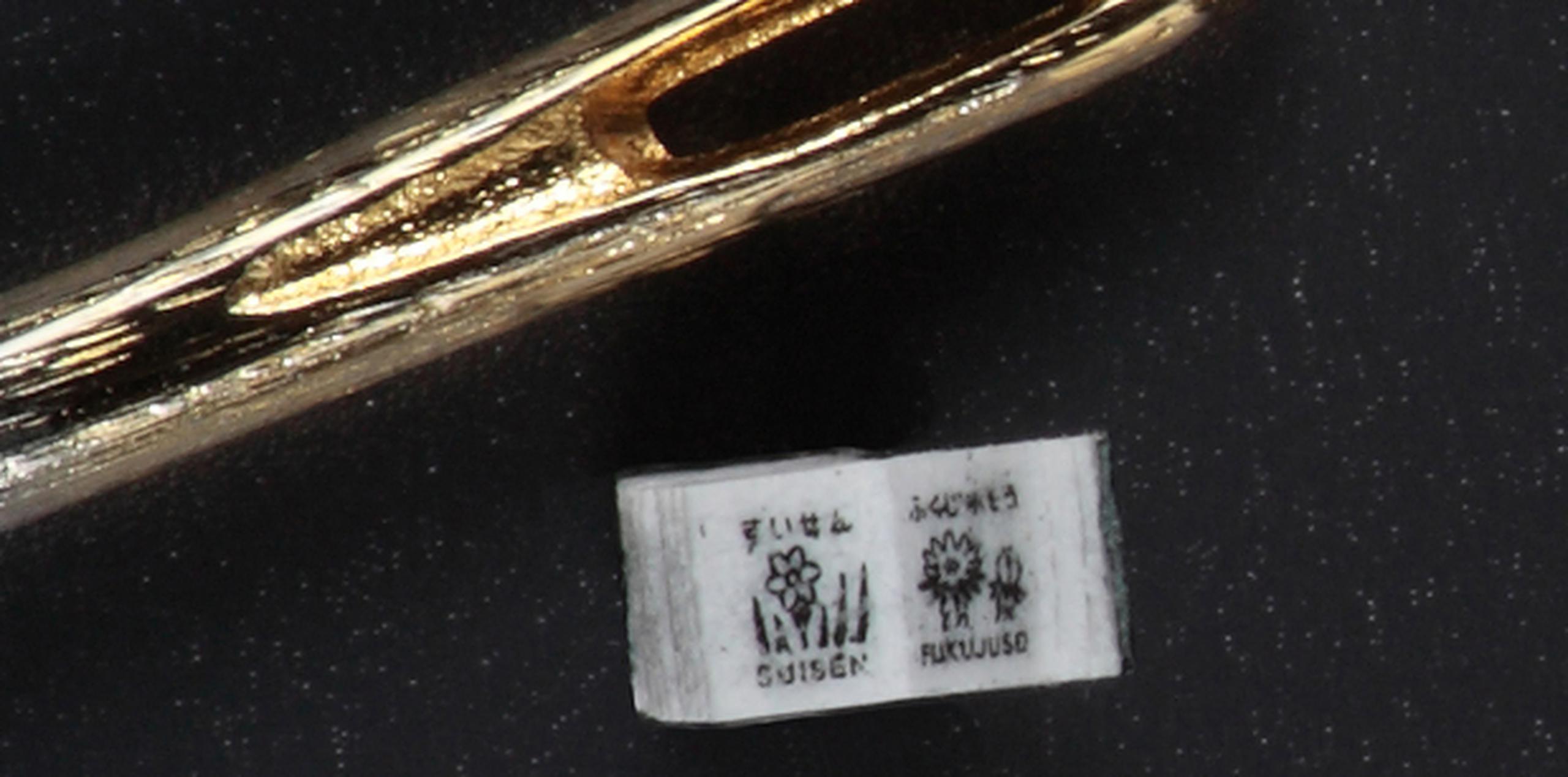 El diminuto libro es mostrado al lado de una aguja de coser. (AFP/Toppan Printing)