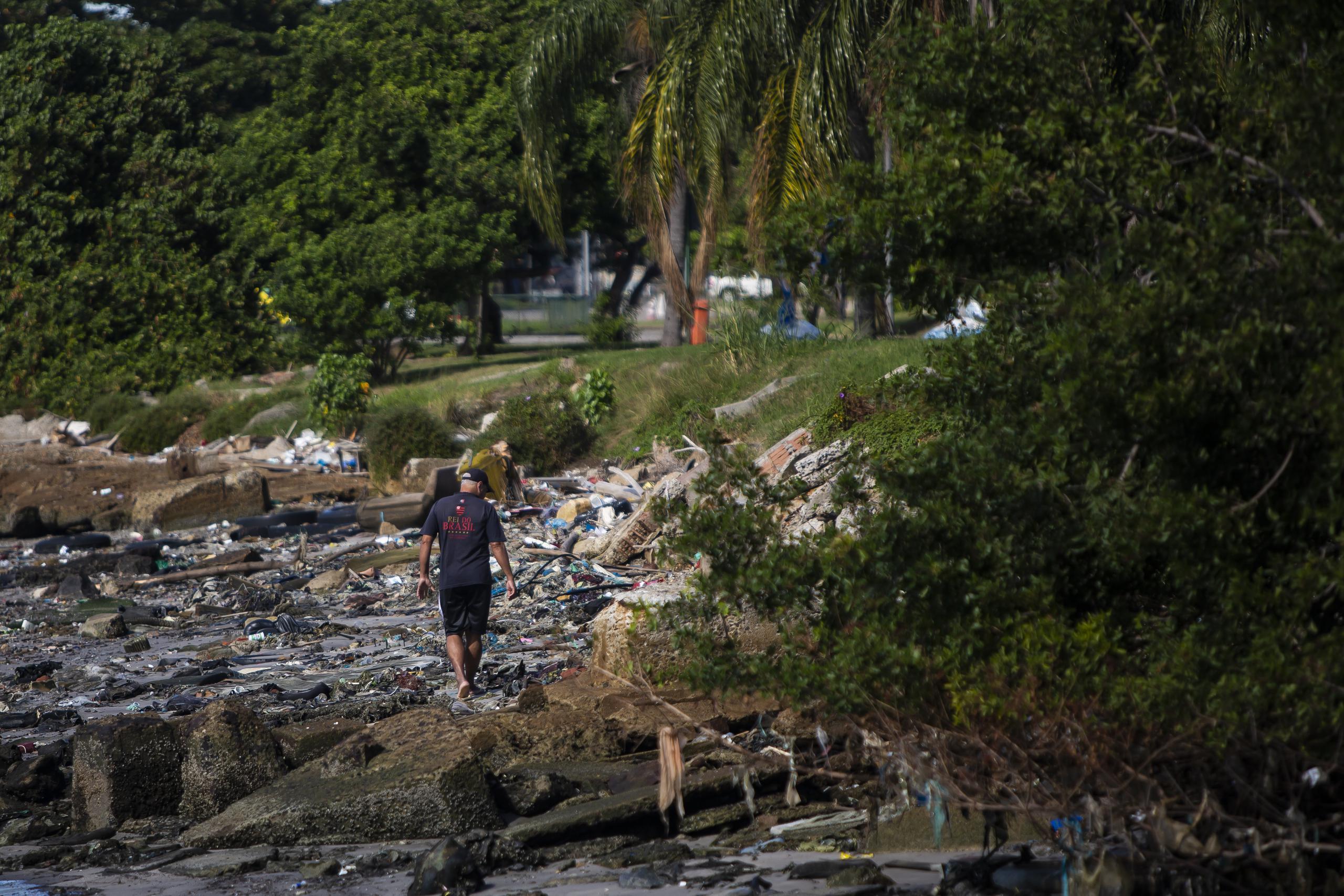 Un hombre camina por un sector de la bahía de Guanabara lleno de basura en Río de Janeiro el 24 de junio del 2021. Los organizadores de los Juegos Olímpico de Río del 2016 no cumplieron su promesa de limpiar el agua de la bahía. (AP Photo/Bruna Prado)