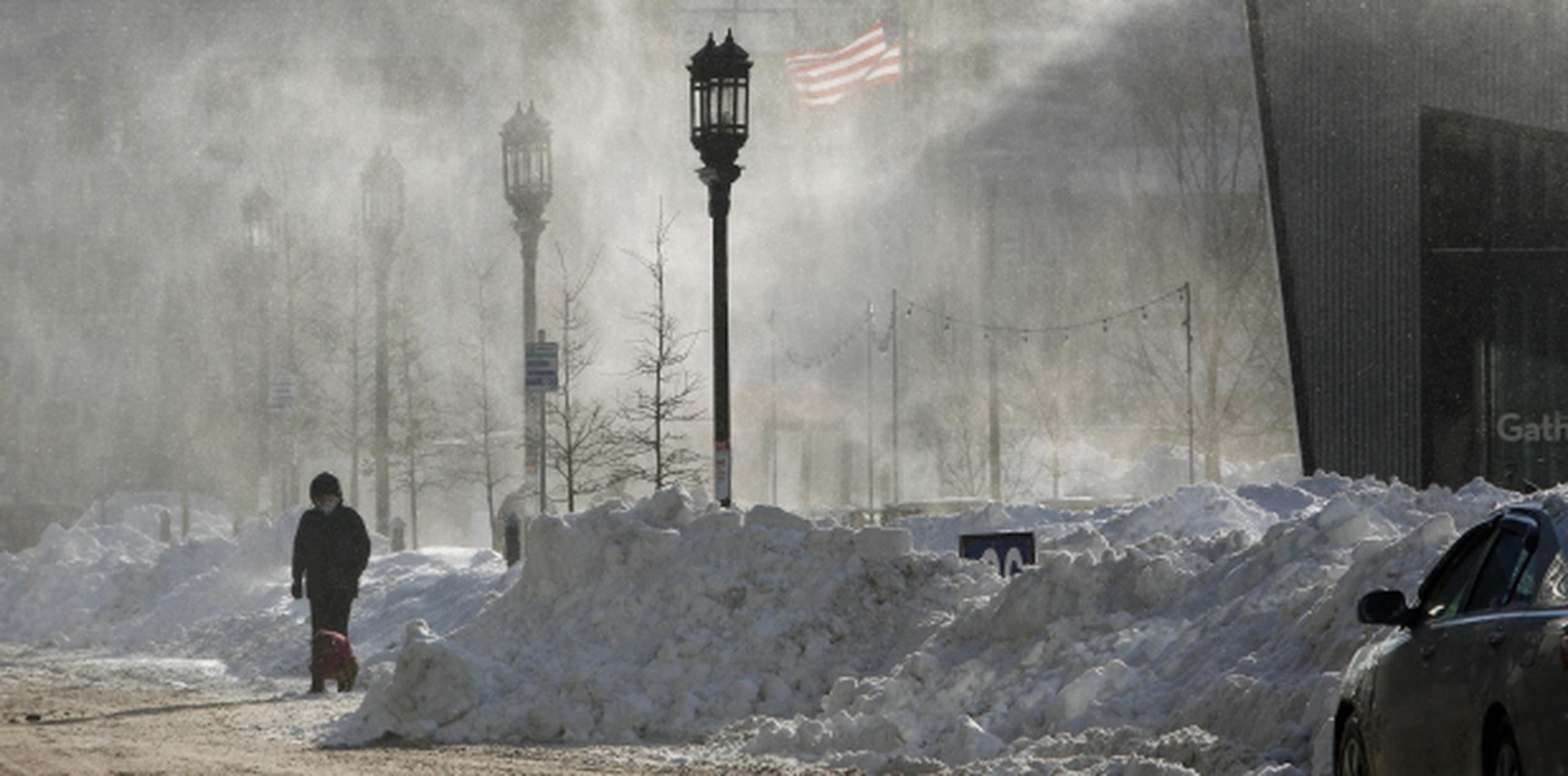 Una persona paseando a un perro por la nieve arada mientras el viento azota, hoy en Boston. (AP / Bill Sikes)