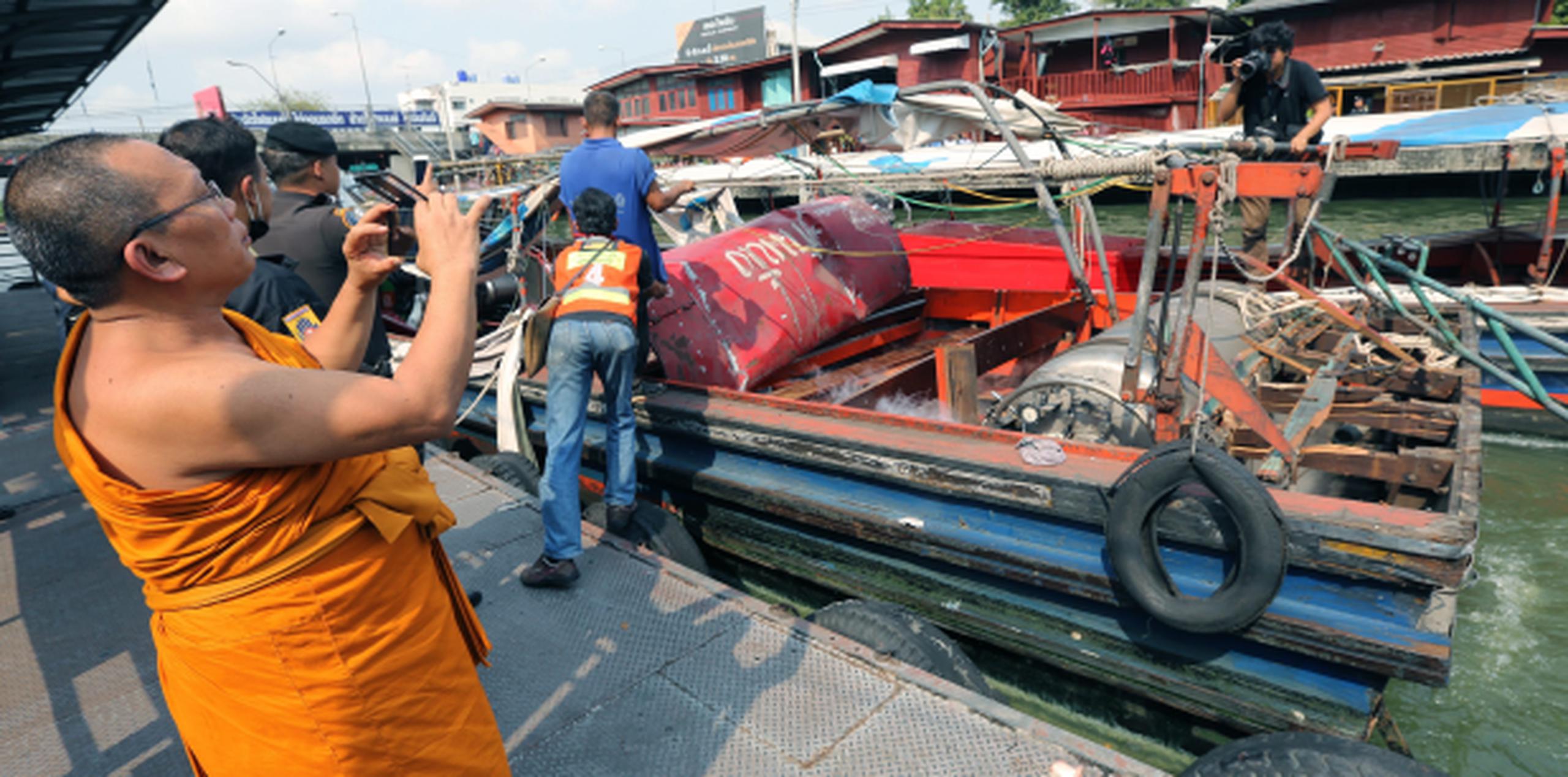 Un monje toma fotos con su celular del bote accidentado. (EFE)