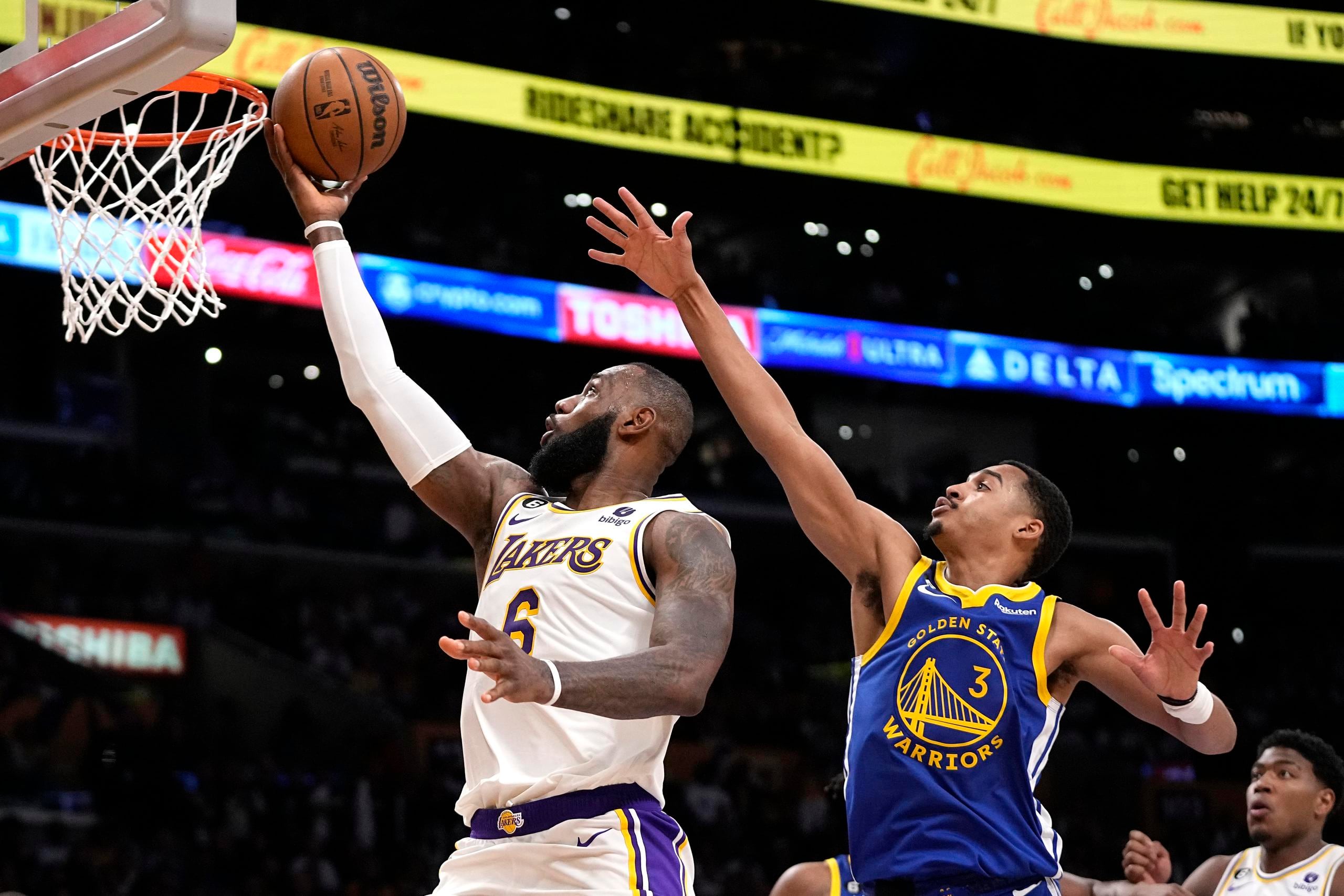LeBron James, de los Lakers de Los Ángeles, se dispone a colar un canasto ante la defensa de Jordan Poole, de los Warriors de Golden State.