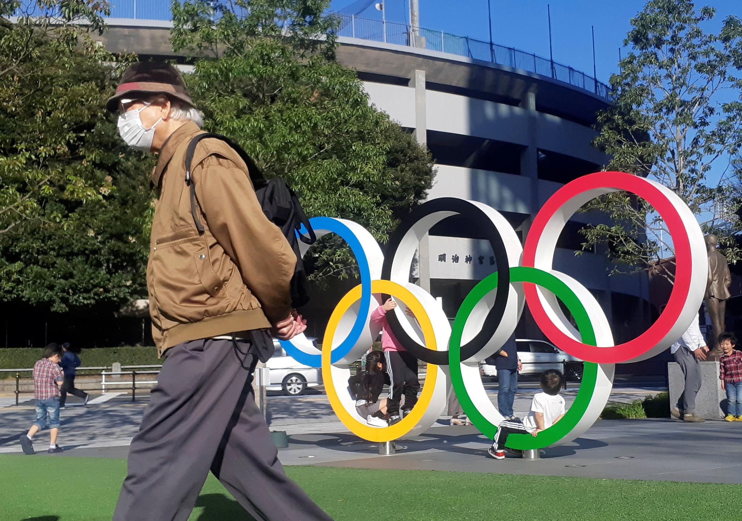 Un hombre protegido por una máscara para evitar posibles contagios da la espalda a los anillos olímpicos instalados en Tokio. Los Juegos Olímpicos de Tokio 2020 se han convertido en un foco de incertidumbre para los japoneses frente a la decisión del COI de continuar los preparativos para las fechas programadas pese a la pandemia del coronavirus.