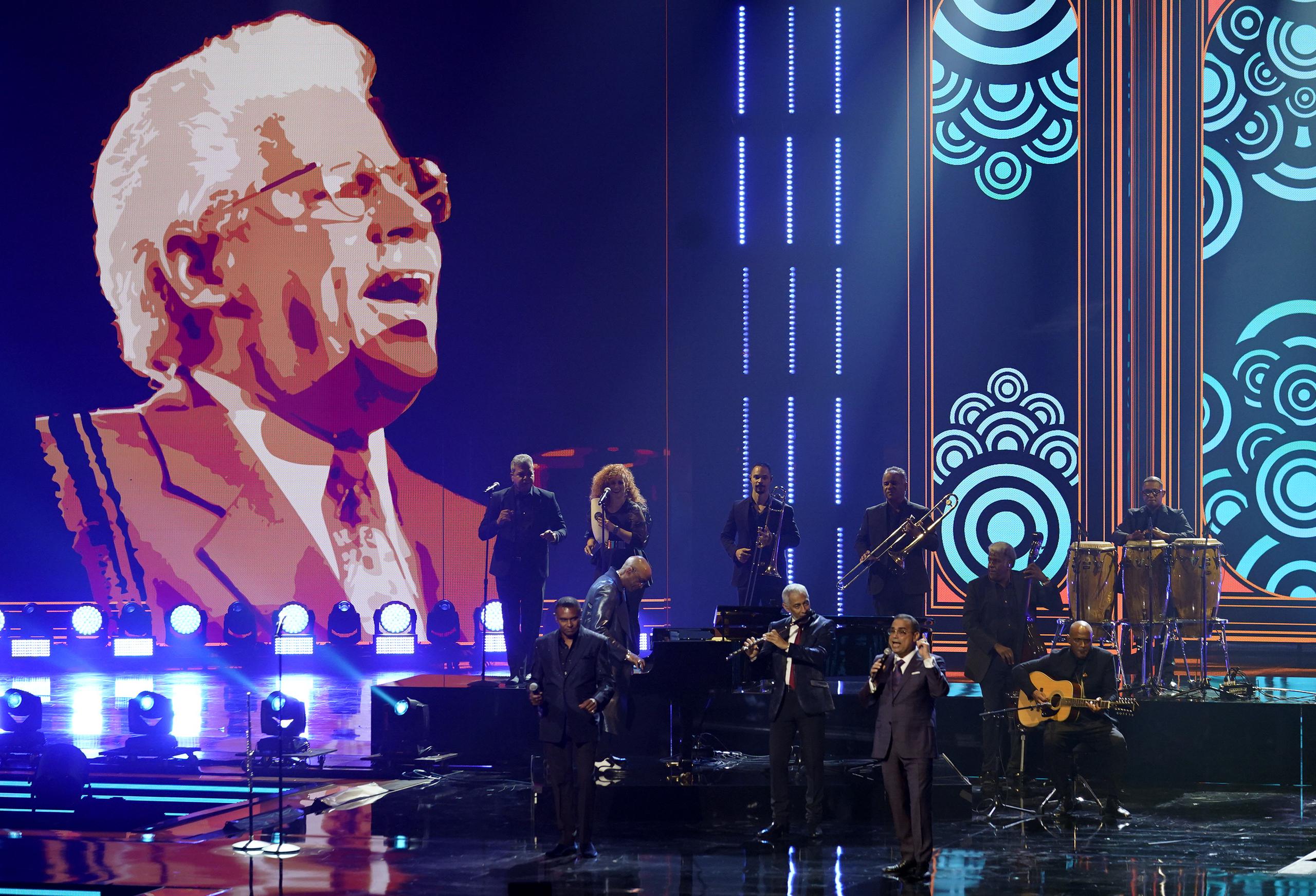José Alberto "El Canario", Néstor Torres y Gilberto Santa Rosa cantan en homenaje al difunto Johnny Pacheco, en pantalla.