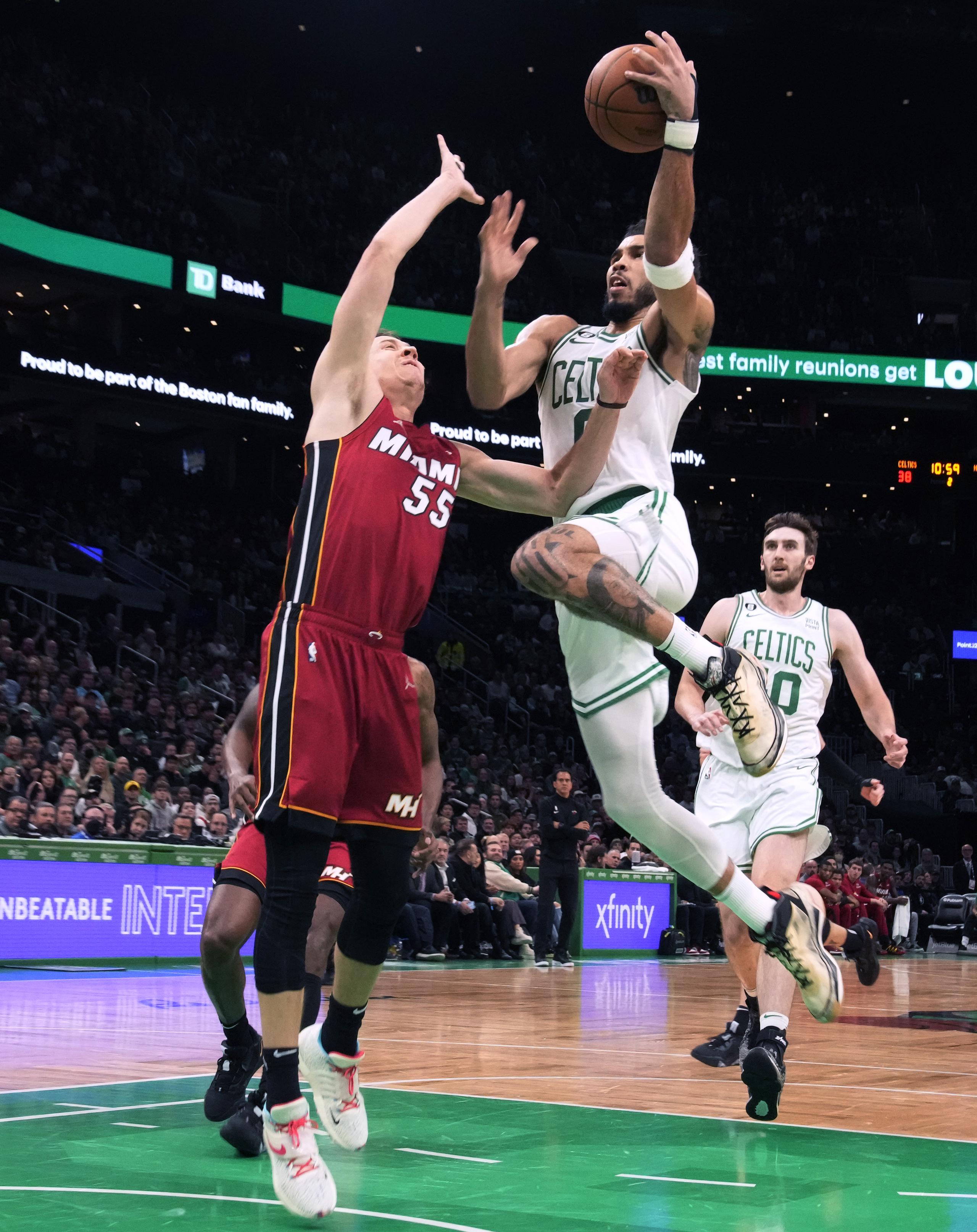 Jayson Tatum, de los Celtics de Boston, con el balón, se dirige hacia el canasto contra la defensa del delantero Duncan Robinson (55), del Heat de Miami.