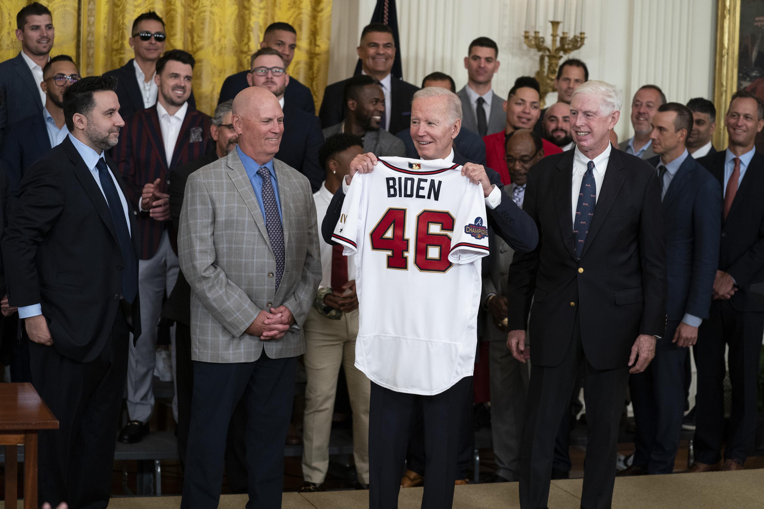 El presidente Joe Biden alza una casaca durante un acto en la Casa Blanca para homenajear a los Braves de Atlanta, campeones de la Serie Mundial.