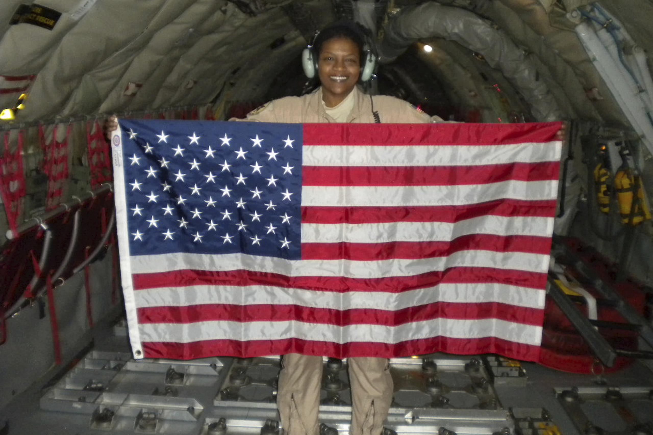 La teniente coronel retirada de la Fuerza Aérea Stephanie Davis sosteniendo una bandera de EEUU durante un vuelo por Pakistán y Afganistán.