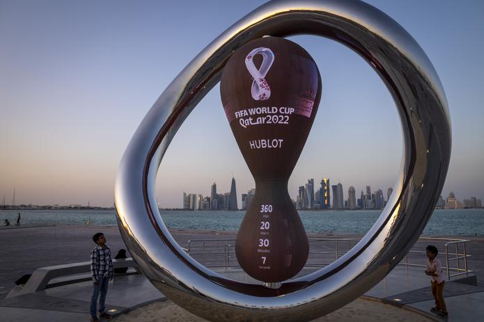 Un par de niños observa el reloj que marca la cuenta regresiva hacia el Mundial de Qatar en Doha, el 22 de noviembre de 2021.