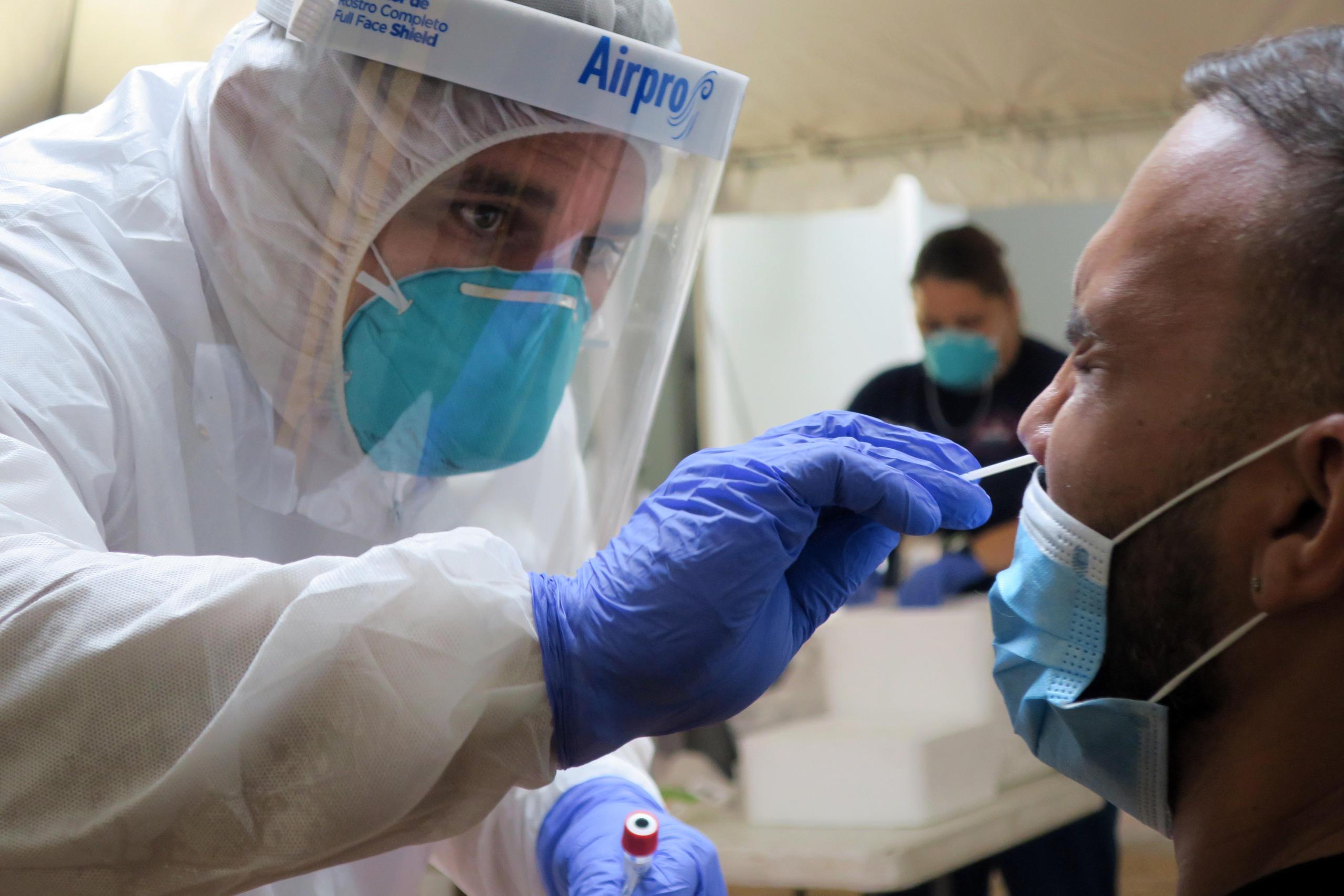Un técnico de laboratorio inserta un hisopo en la nariz de un paciente para la prueba del coronavirus.