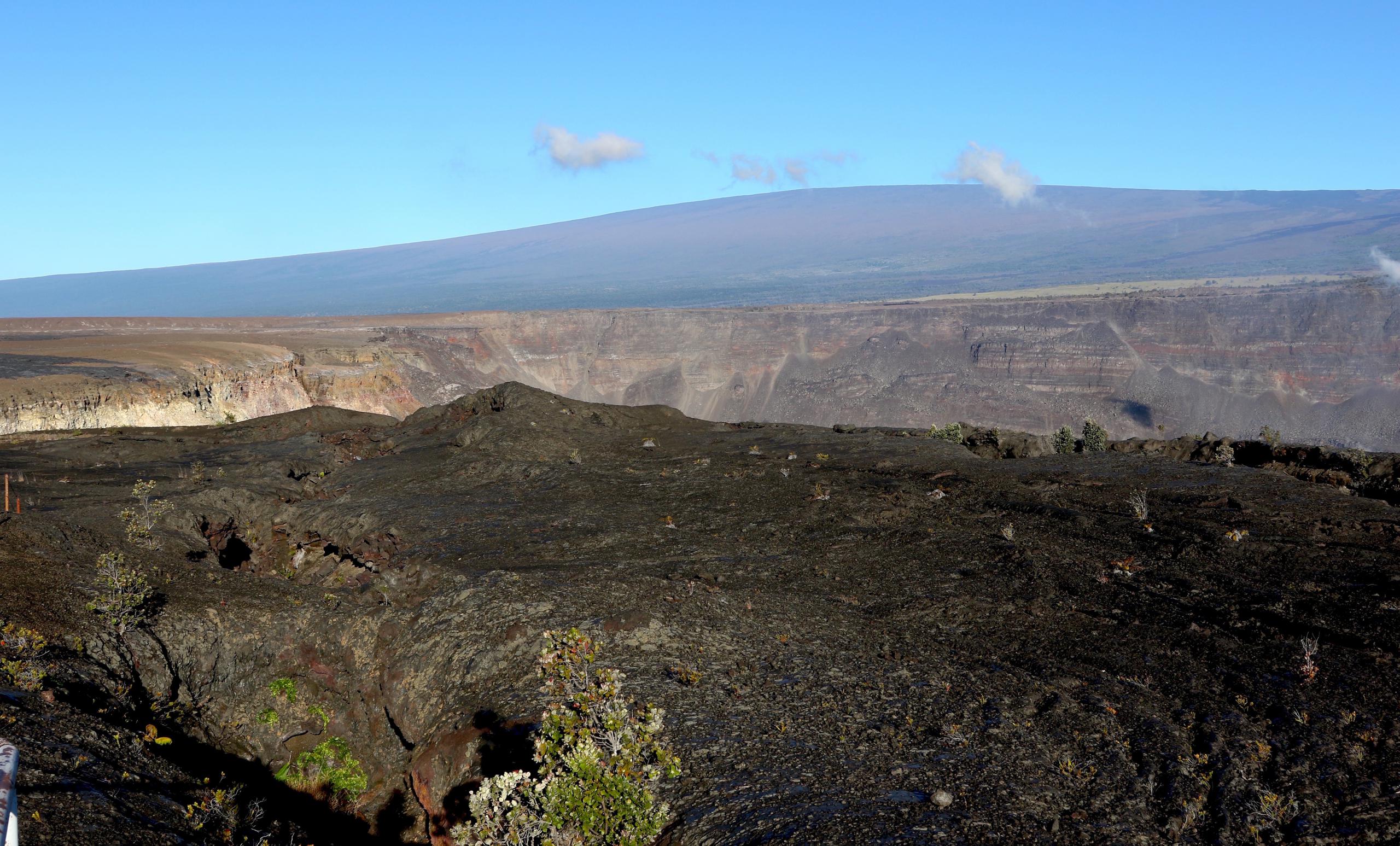 El volcán Mauna Loa, al fondo, eclipsa la cumbre del volcán Kilauea (al centro) en el parque nacional de los volcanes en Hawai el 25 de abril de 2019. (AP Foto/Caleb Jones, Archivo)