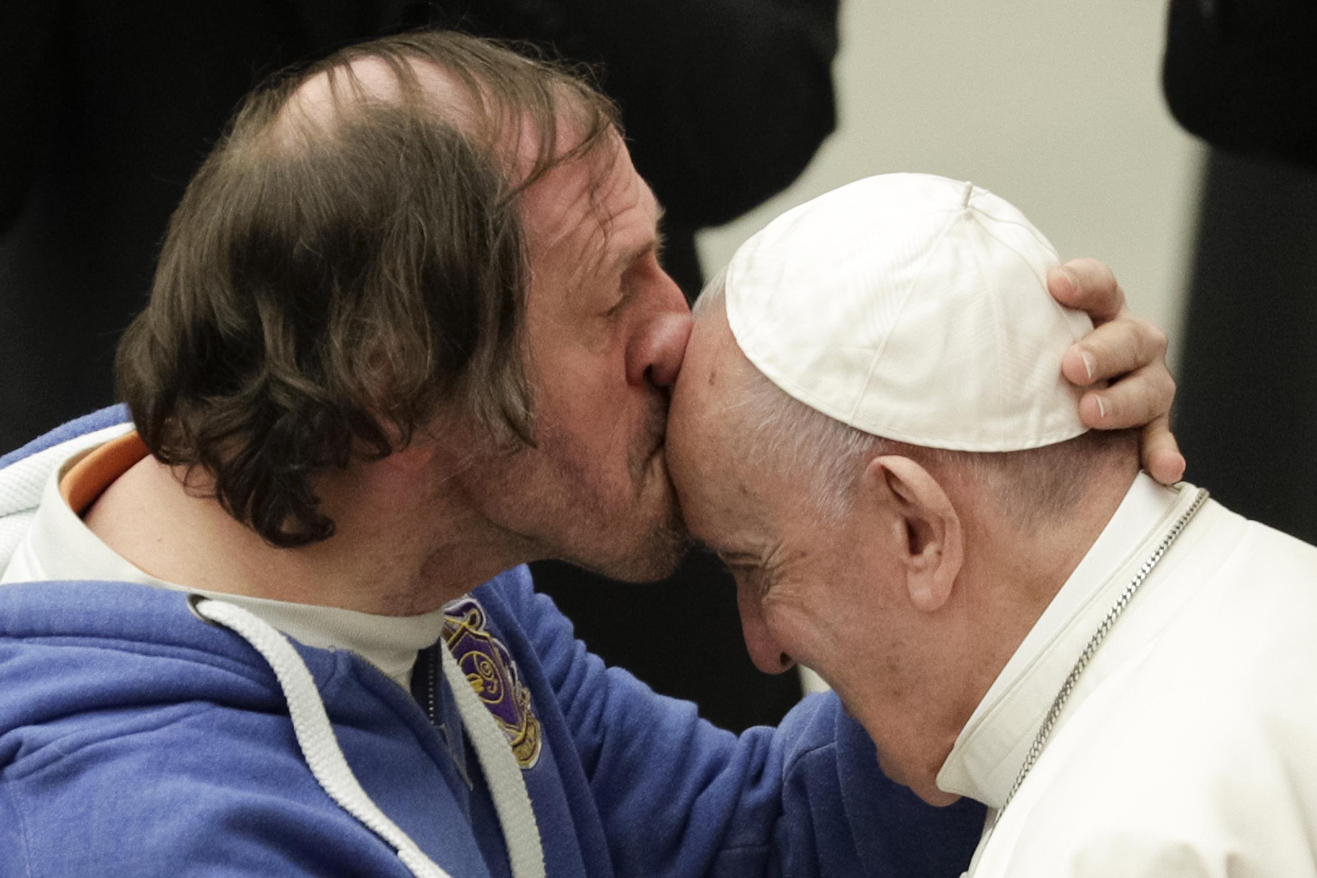 Un hombre besa al papa Francisco en la frente, en el Vaticano