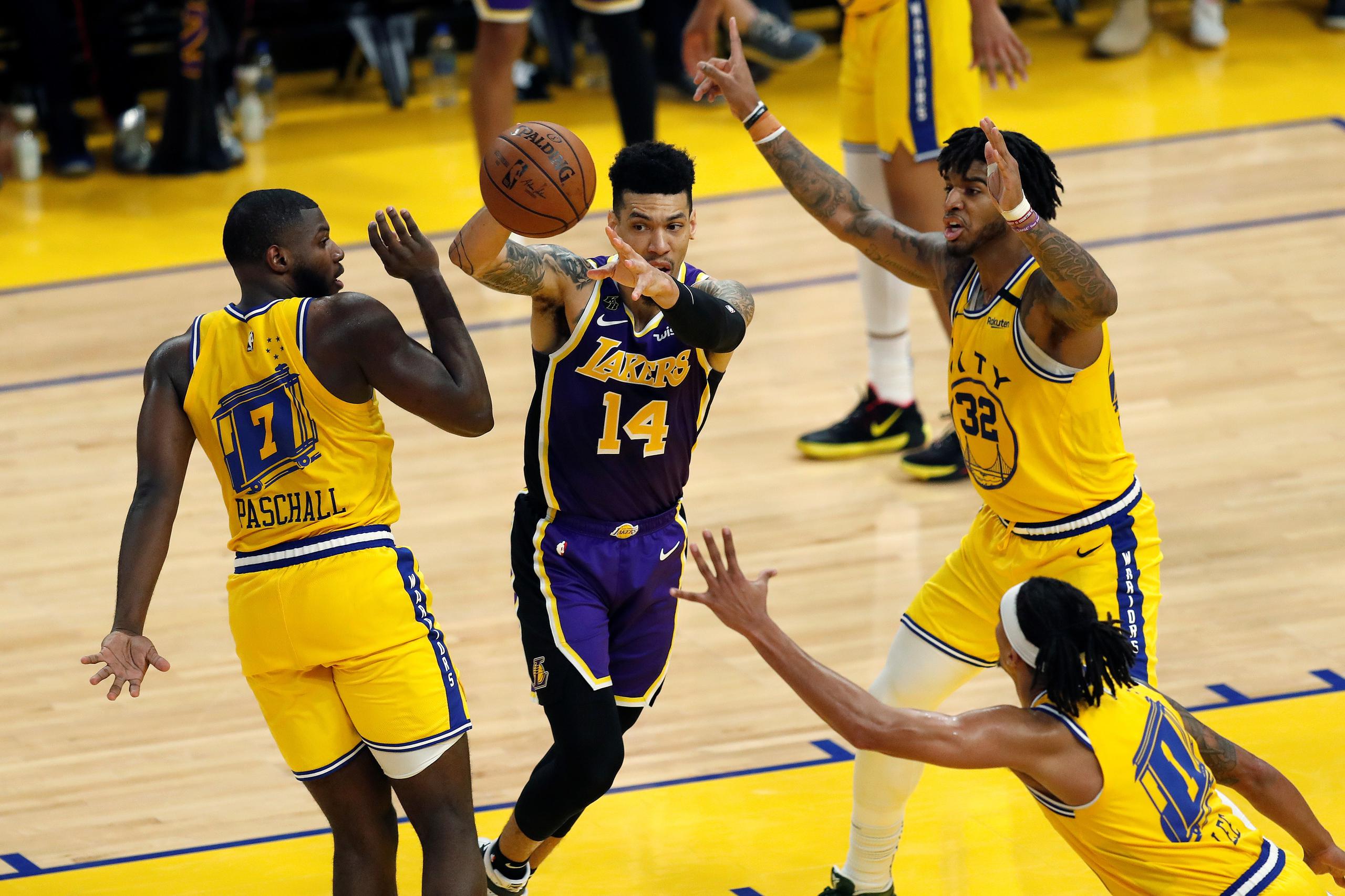 El armador de los Lakers, Danny Green hace un pase entre tres jugadores de los Warriors.