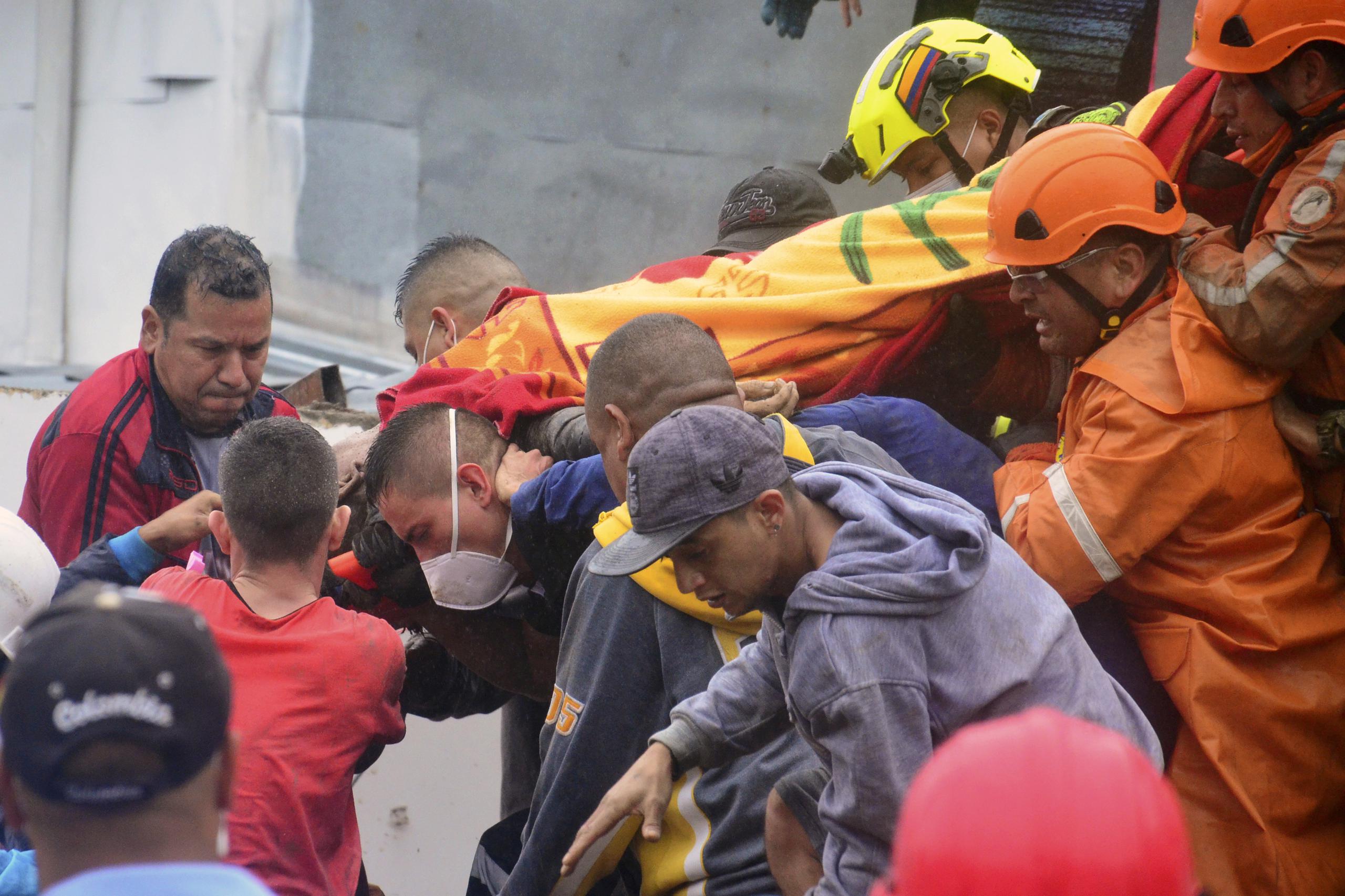 Los equipos de rescate cargan a un sobreviviente donde una ladera debilitada por la lluvia se derrumbó sobre las casas de las personas en Pereira, Colombia.