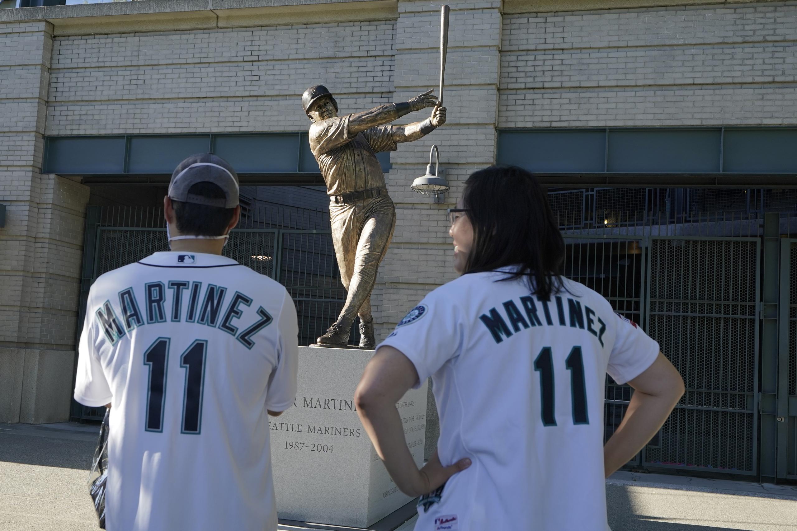Dos fanáticos observan la estatua que ubica en las afueras del estadio en la calle que lleva el nombre del pelotero boricua.
