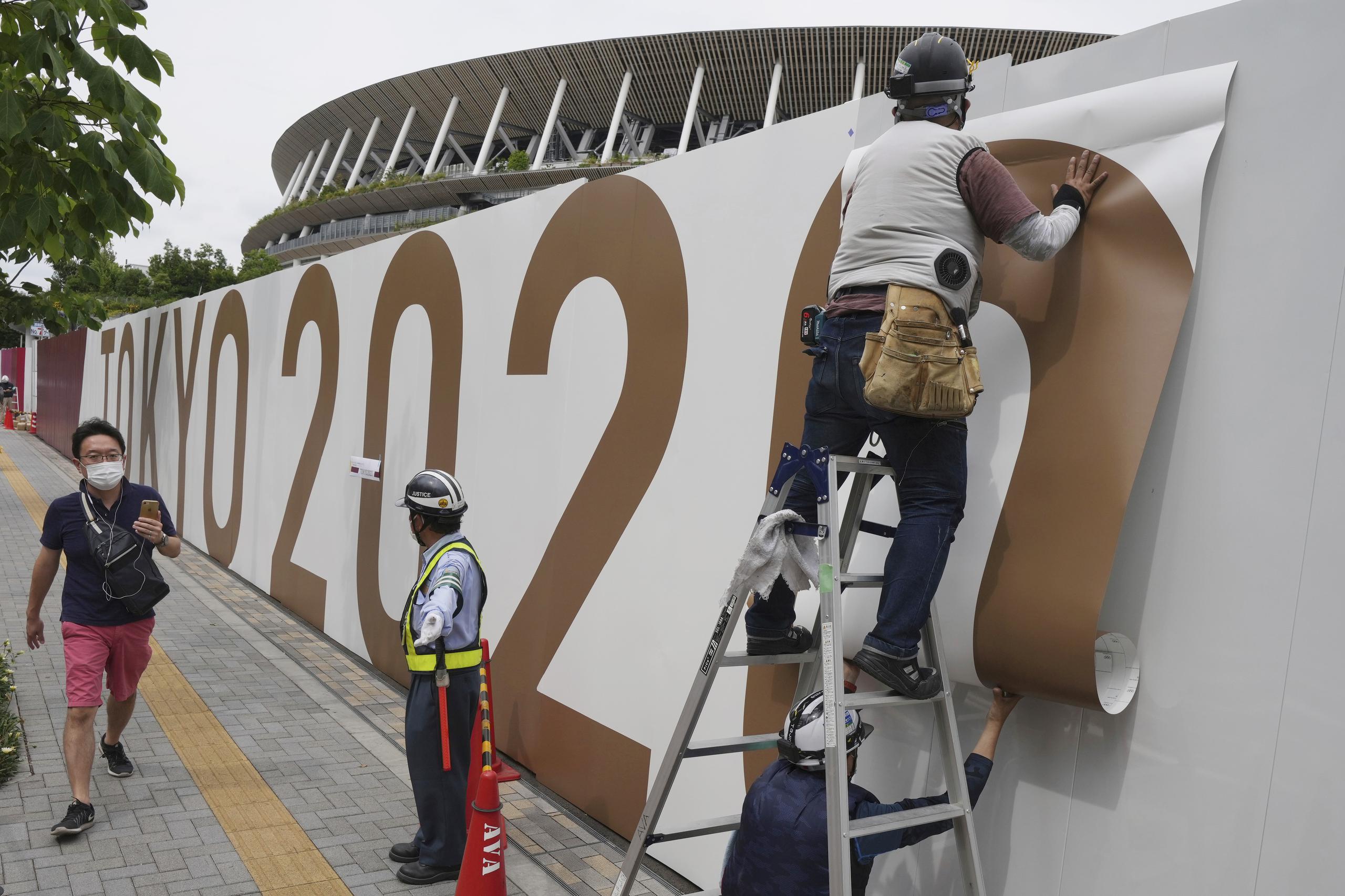 Trabajadores pegan unas letras en la pared del Estadio Nacional, donde la ceremonia de apertura y muchos otros eventos están programados para los Juegos Olímpicos de Tokio 2020.