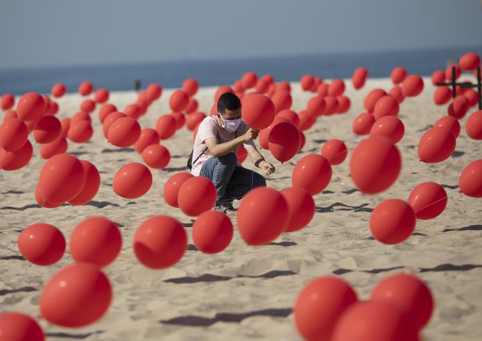 Un hombre ayuda a colocar globos rojos en la arena de la playa de Copacabana en una manifestación organizada por Río de Paz para honrar a las víctimas del COVID-19.
