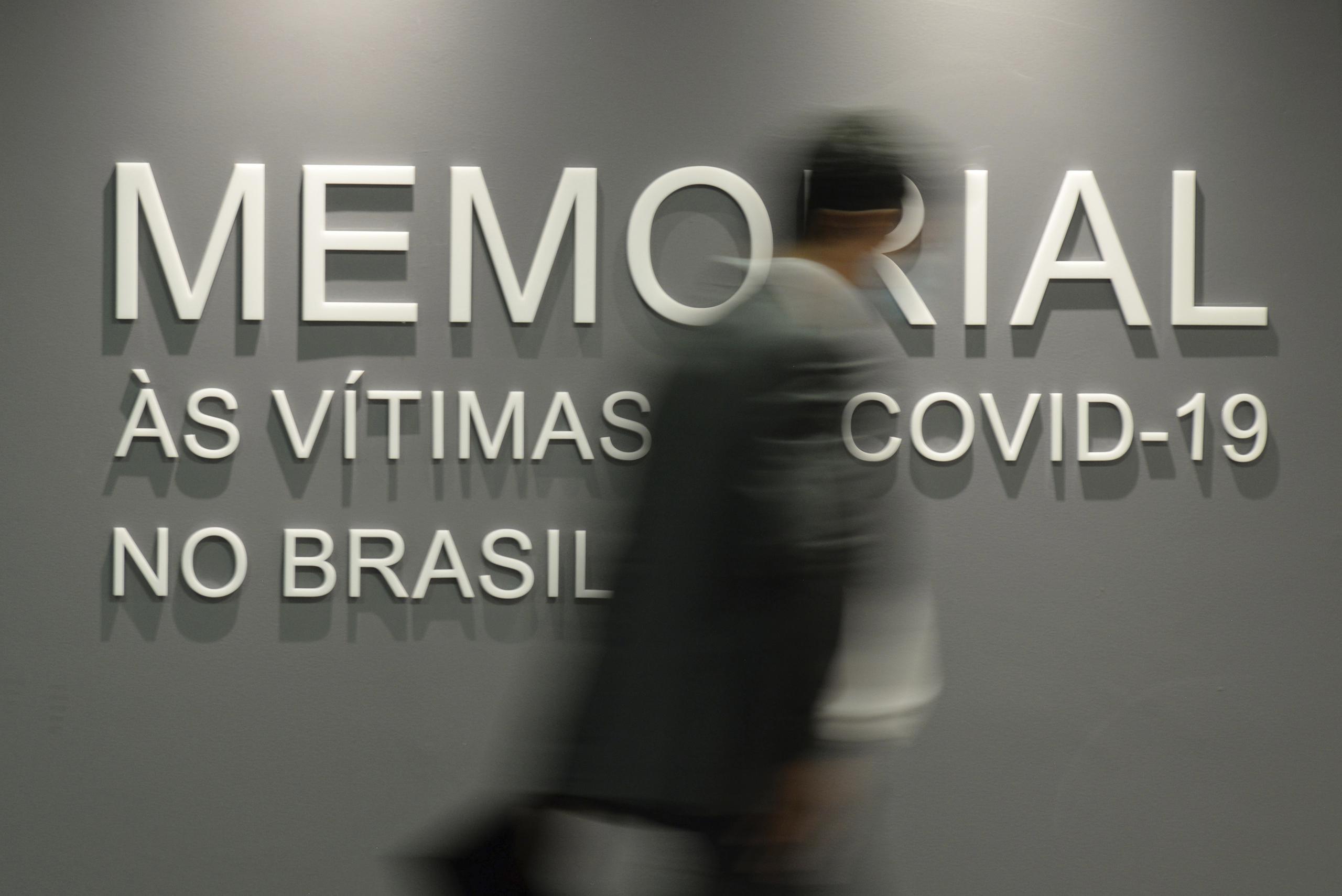 Un hombre camina frente a un muro que dice en portugués: "Memorial para las víctimas del COVID-19 en Brasil", en el edificio del Senado en Brasilia, Brasil.