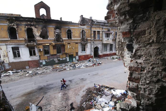 Niños caminan entre edificios destruidos en Mariúpol, que está bajo control ruso en el este de Ucrania, el 25 de mayo de 2022.