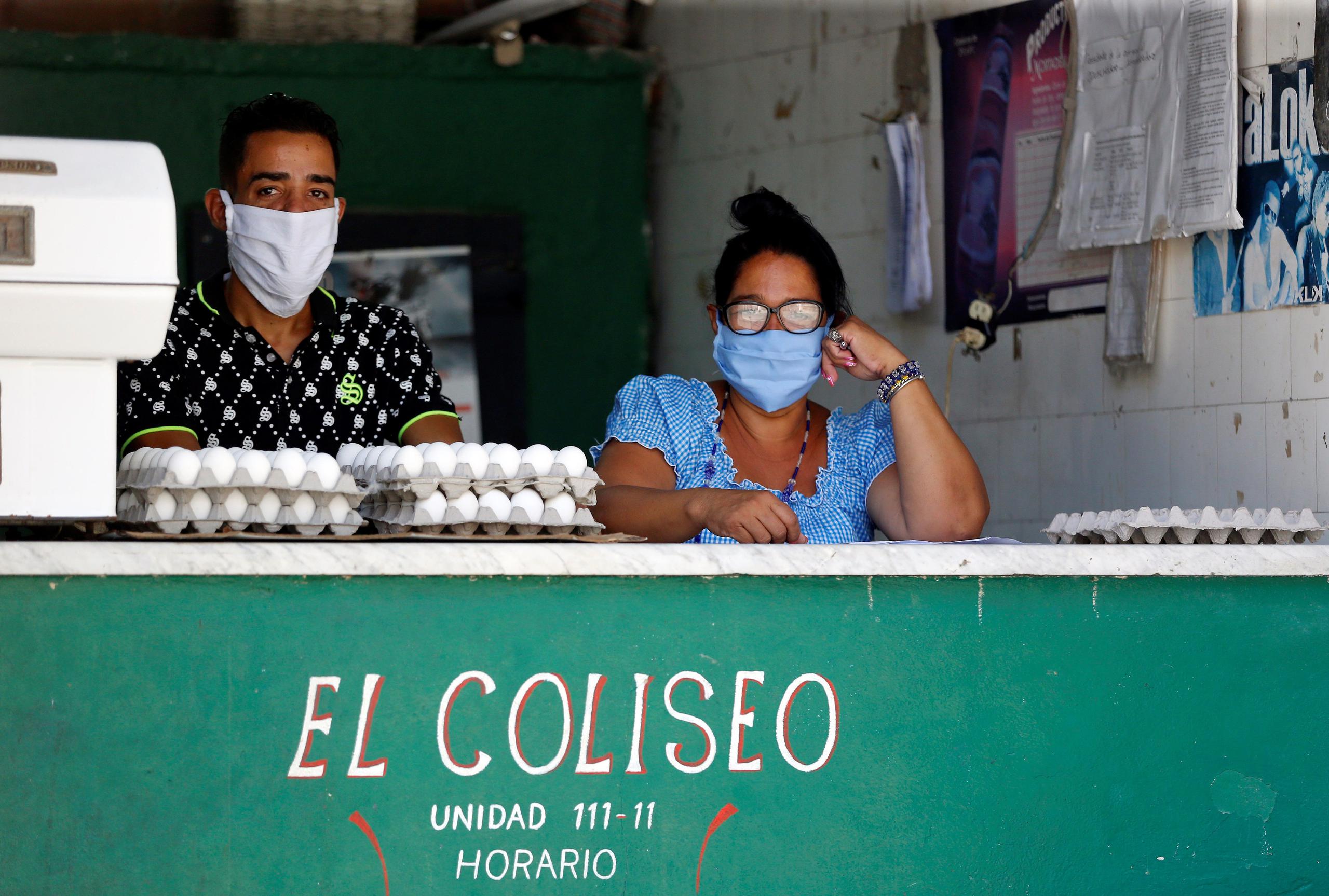 Una mujer y un hombre utilizan tapabocas este lunes mientras atienden en un almacén de alimentos, en La Habana (Cuba).