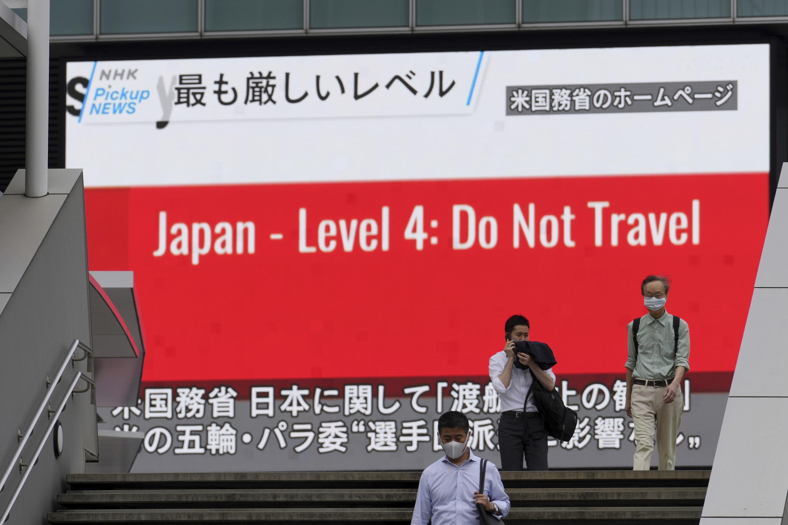 Transeúntes con mascarillas en Tokio pasan junto a una pantalla que muestra la noticia de que Estados Unidos advirtió a sus ciudadanos que no deben viajar a Japón.