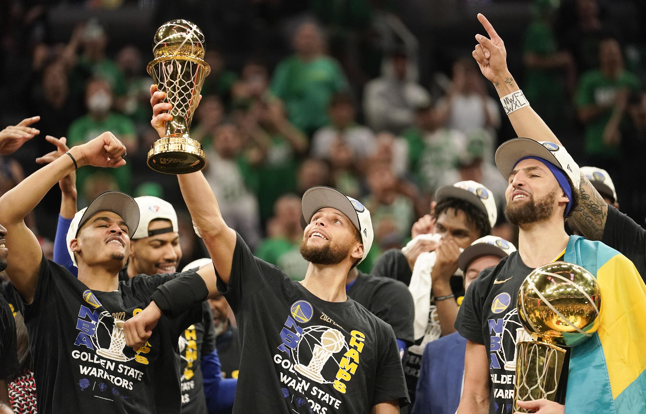 Stephen Curry, al centro, levanta su primer premio al Jugador Más Valioso de la serie final de la NBA.