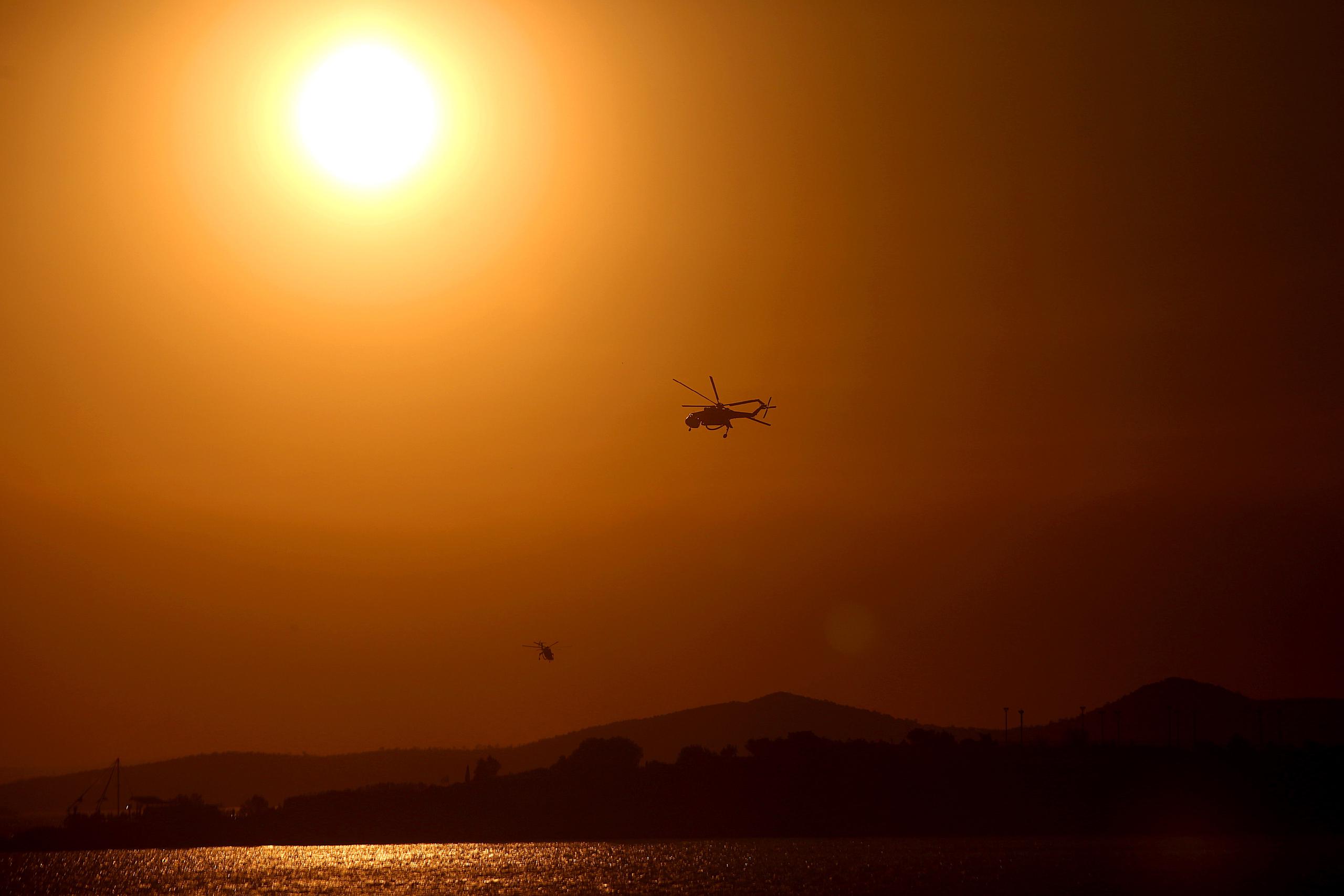 Un helicóptero busca recargar su depósito de agua en el mar para seguir combatiendo los incendios en Grecia. (EFE/EPA/ORESTIS PANAGIOTOU)