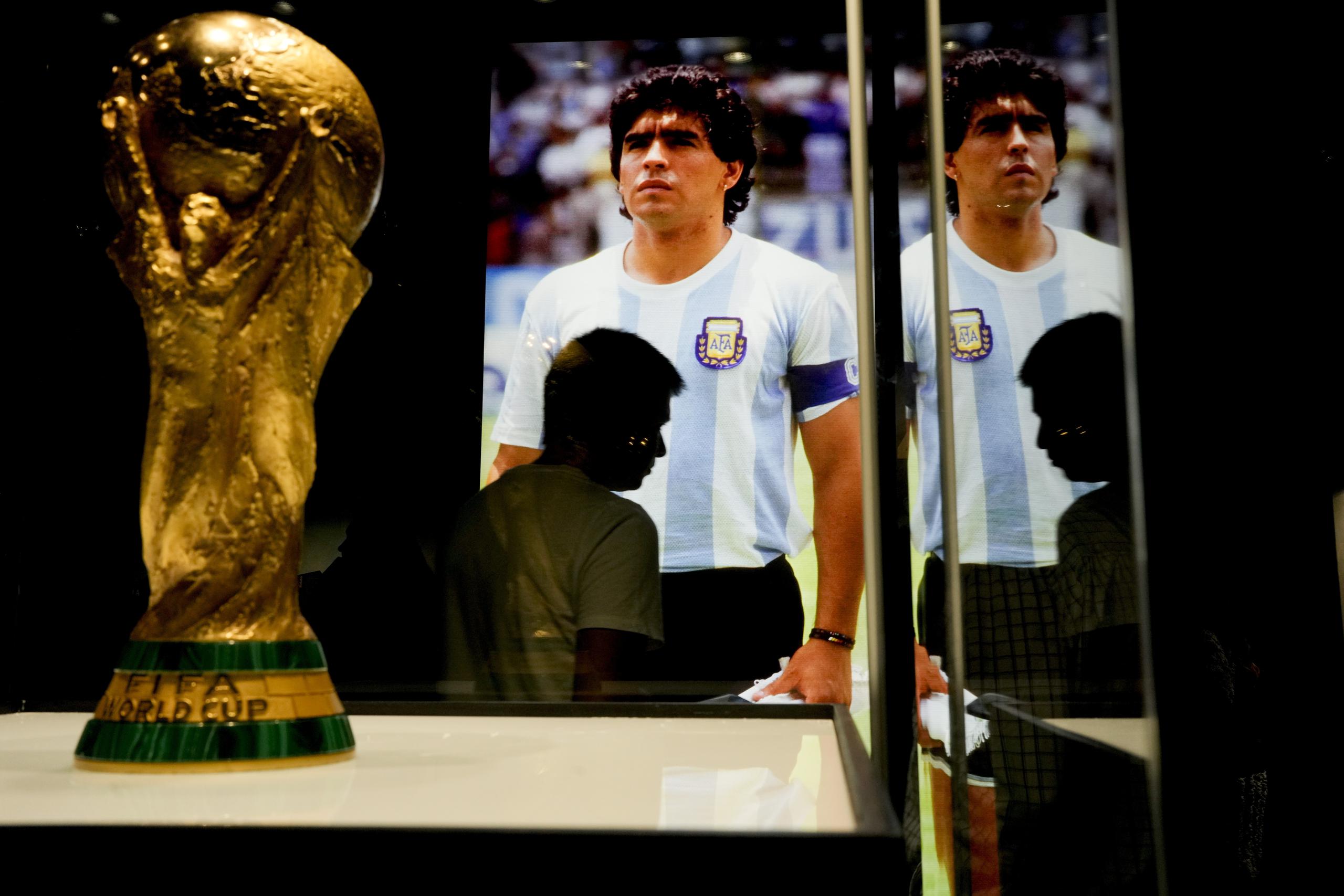 Una réplica del trofeo del Mundial de 1986 colocada frente a una foto de Diego Maradona, el miércoles 5 de abril de 2023, en Buenos Aires. La primera exhibición oficial dedicada a los tres títulos mundiales conquistados por Argentina en 1978, 1986 y 2022 ha sido inaugurada en Buenos Aires. (AP Foto/Natacha Pisarenko)